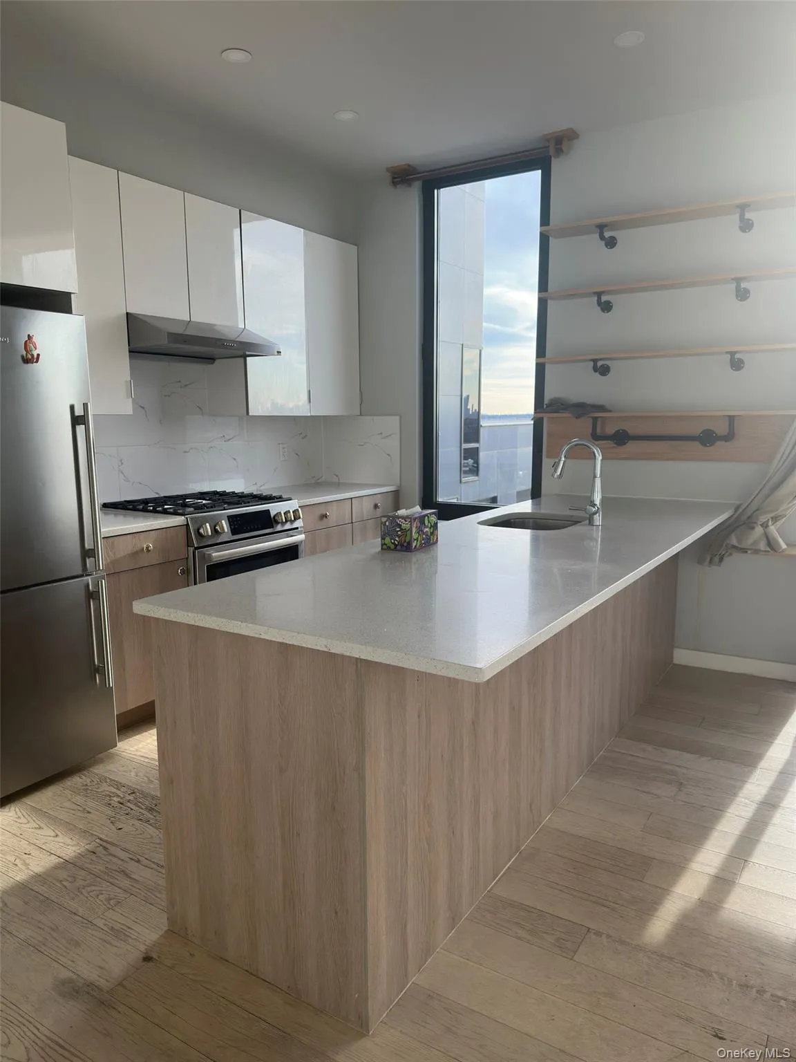 Kitchen with backsplash, appliances with stainless steel finishes, light stone counters, modern cabinets, and white cabinets Kitchen with backsplash, appliances with stainless steel finishes, light stone counters, modern cabinets, and white cabinets