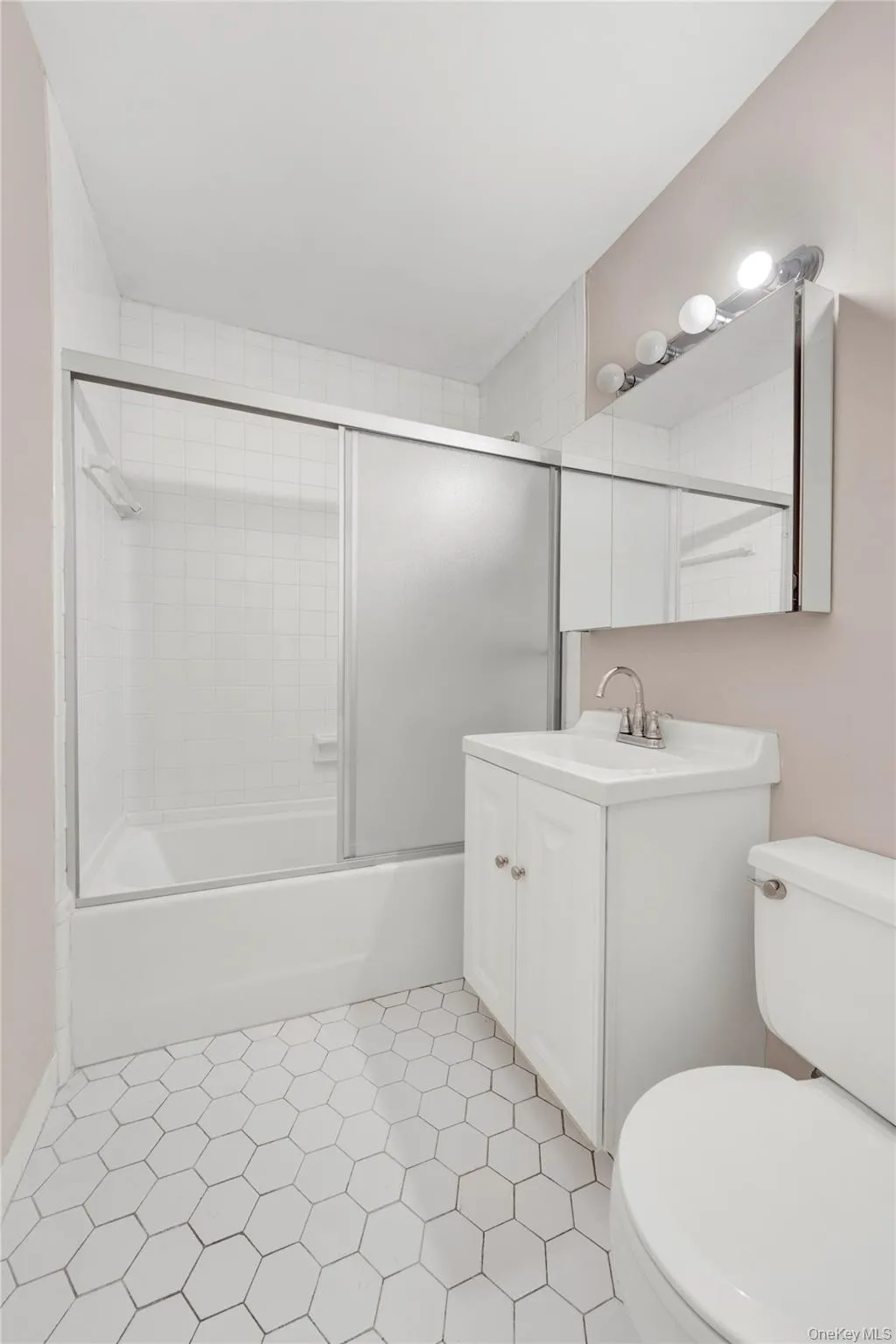 Full bath featuring vanity, bath / shower combo with glass door, and light tile patterned floors Full bath featuring vanity, bath / shower combo with glass door, and light tile patterned floors