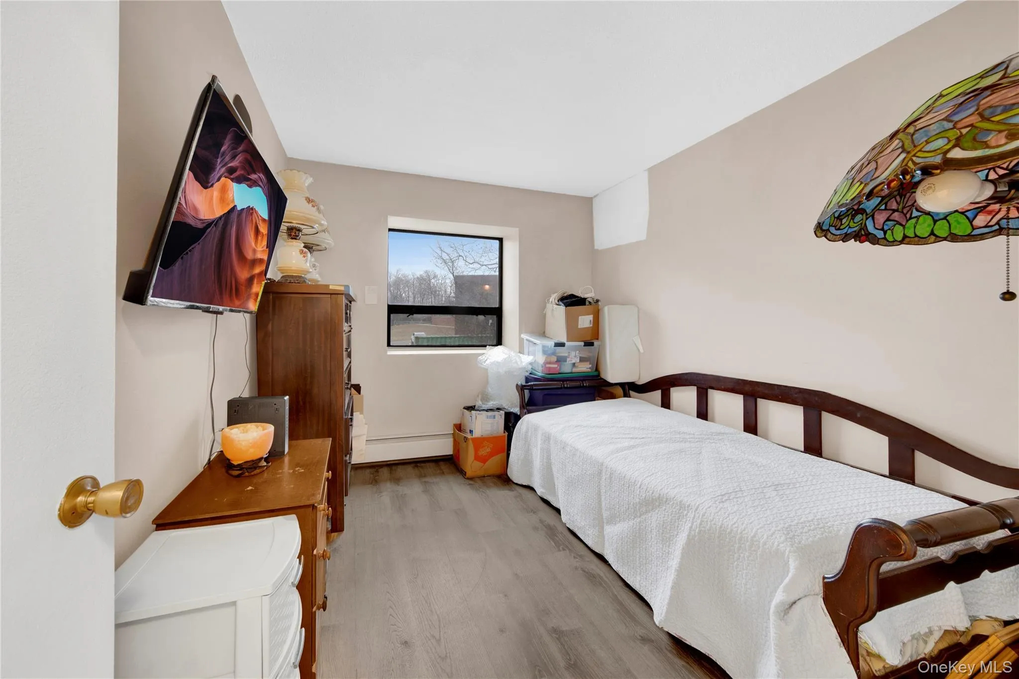 Bedroom featuring wood finished floors and a baseboard heating unit Bedroom featuring wood finished floors and a baseboard heating unit