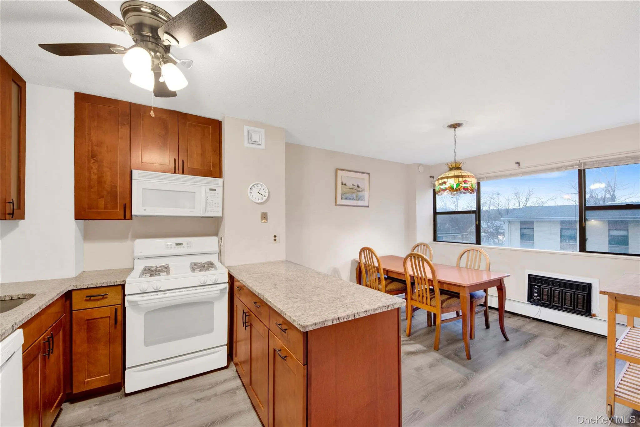 Kitchen with brown cabinetry, white appliances, and light stone countertops Kitchen with brown cabinetry, white appliances, and light stone countertops