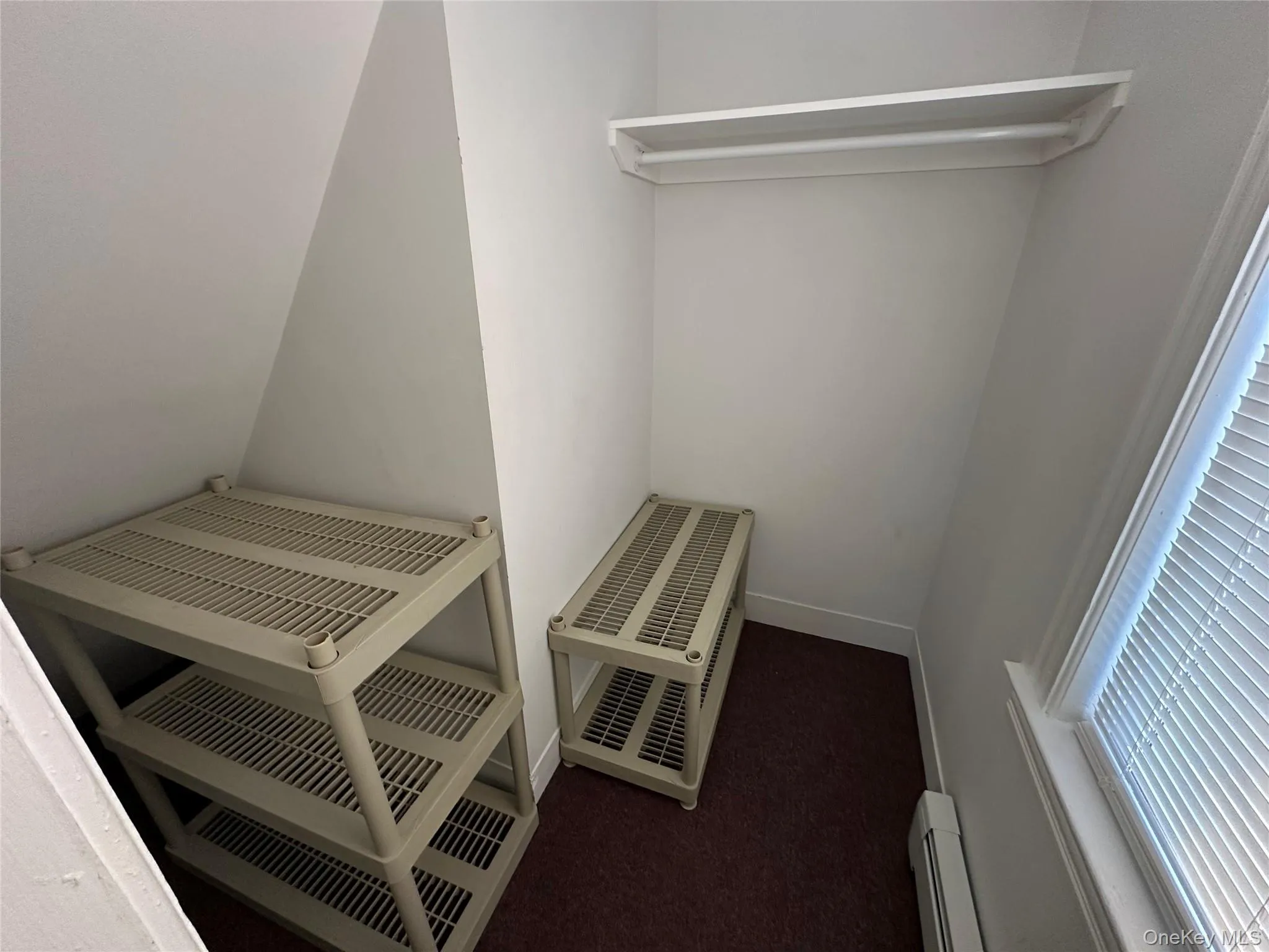 Spacious closet with a baseboard radiator and dark colored carpet Spacious closet with a baseboard radiator and dark colored carpet