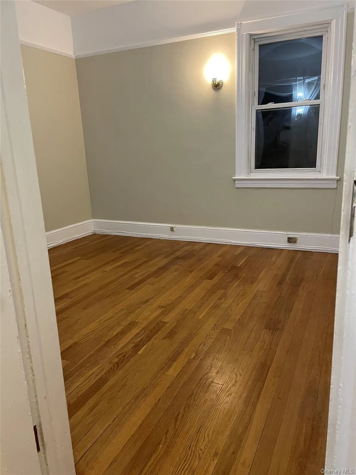 Spare room with dark wood-style flooring and baseboards Spare room with dark wood-style flooring and baseboards