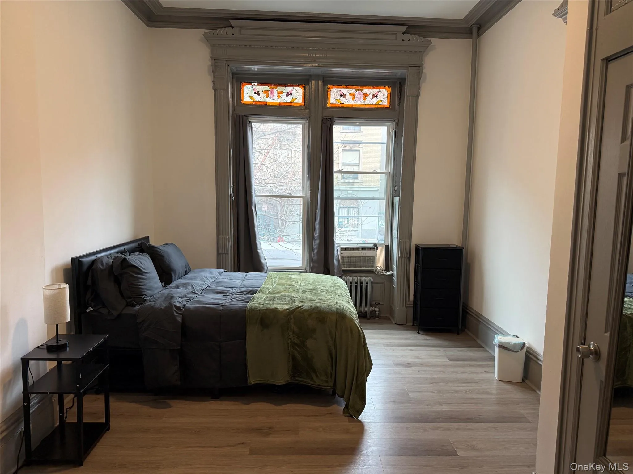 Bedroom with wood finished floors, radiator, and ornamental molding Bedroom with wood finished floors, radiator, and ornamental molding