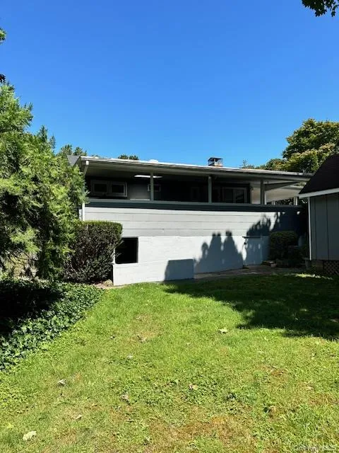 Rear view of house with a lawn, a chimney, and a sunroom Rear view of house with a lawn, a chimney, and a sunroom