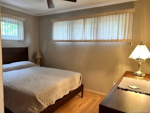 Bedroom featuring light wood finished floors, ornamental molding, and a ceiling fan Bedroom featuring light wood finished floors, ornamental molding, and a ceiling fan
