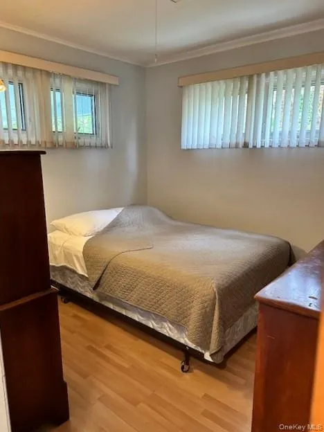 Bedroom with ornamental molding and wood finished floors Bedroom with ornamental molding and wood finished floors