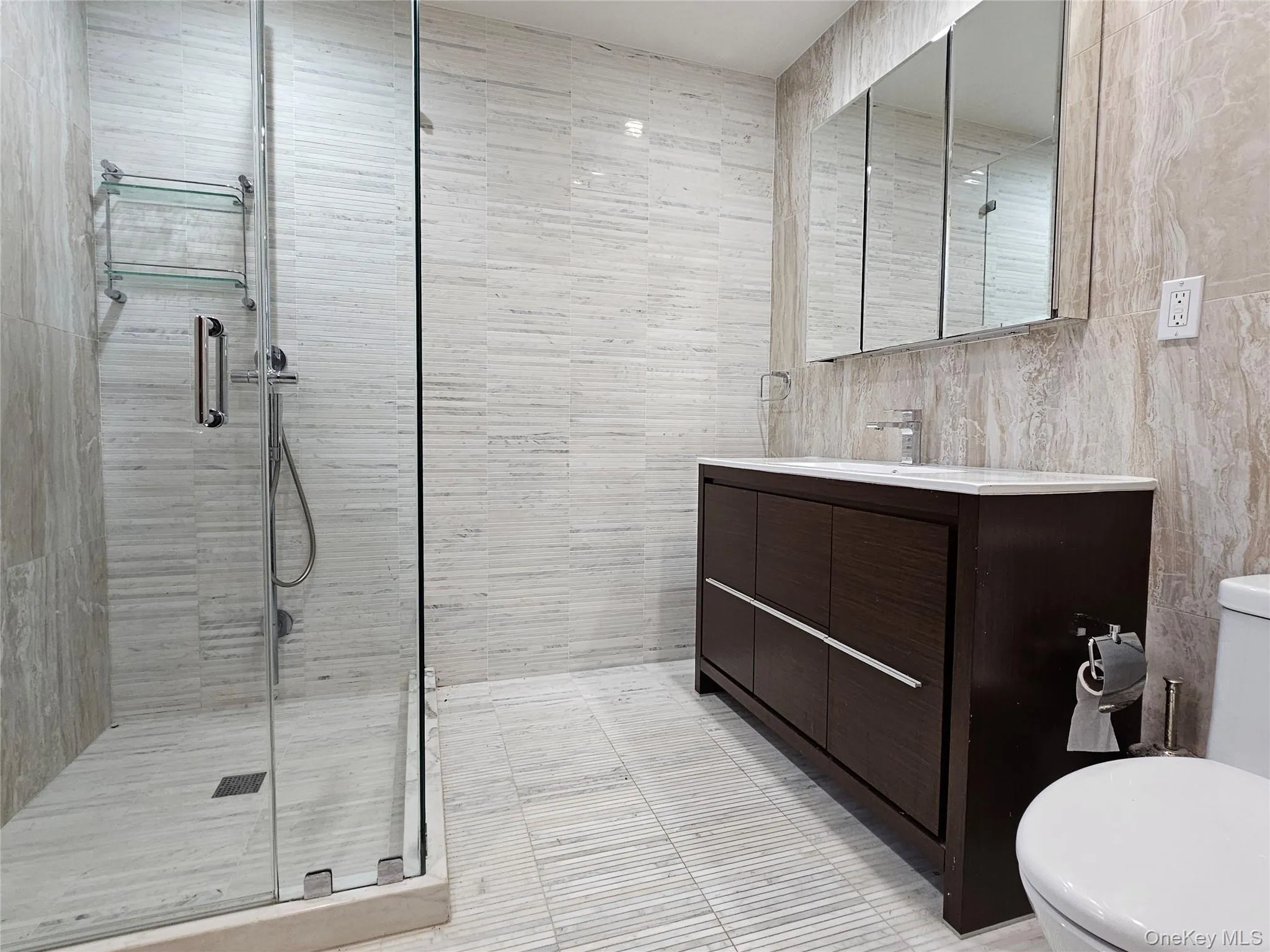 Full bathroom with vanity, a shower stall, and tile walls Full bathroom with vanity, a shower stall, and tile walls