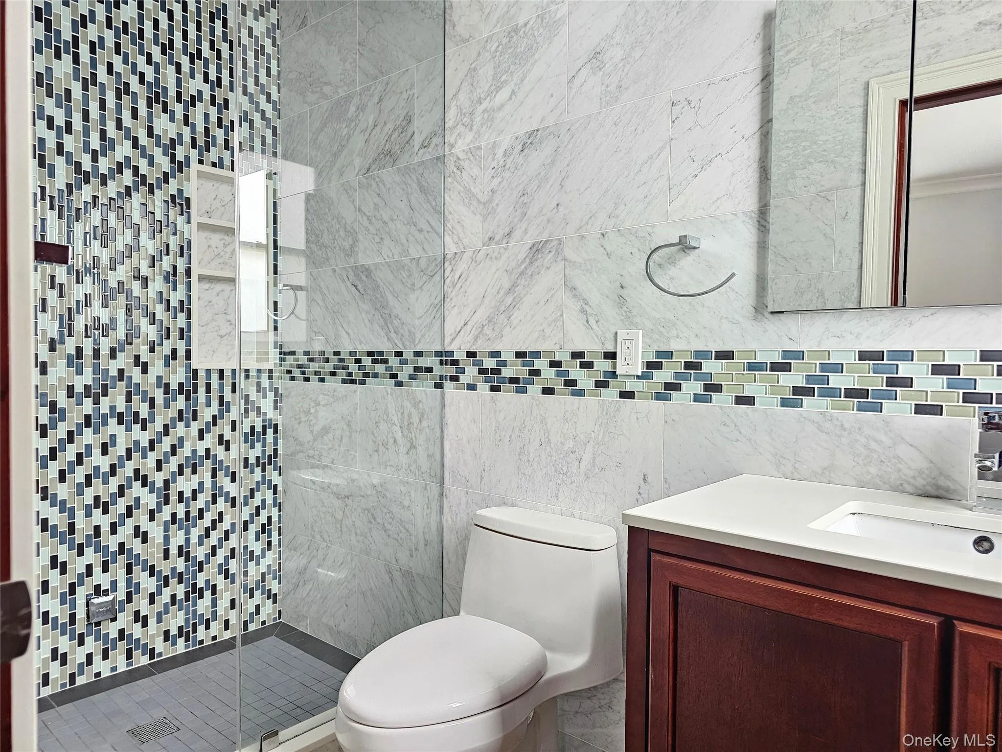 Bathroom featuring vanity, a stall shower, and tile walls Bathroom featuring vanity, a stall shower, and tile walls