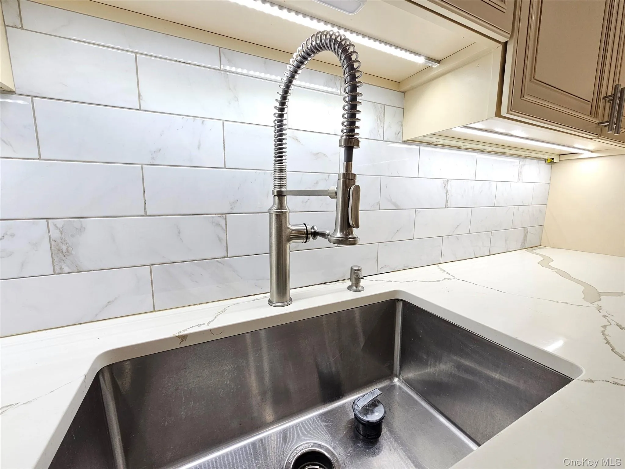 Kitchen view of light stone counters and decorative backsplash Kitchen view of light stone counters and decorative backsplash