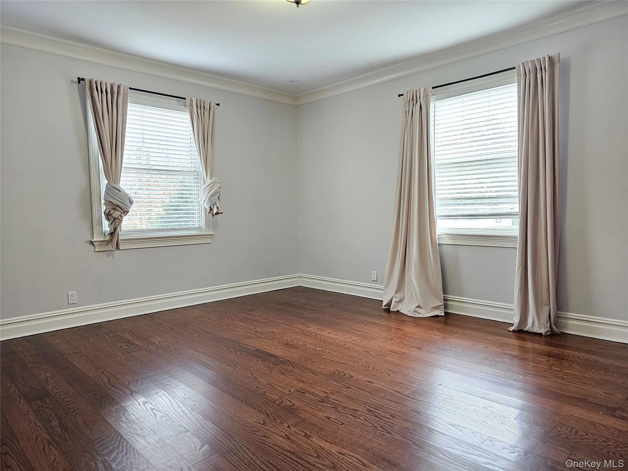 Empty room with crown molding and dark wood-style flooring Empty room with crown molding and dark wood-style flooring