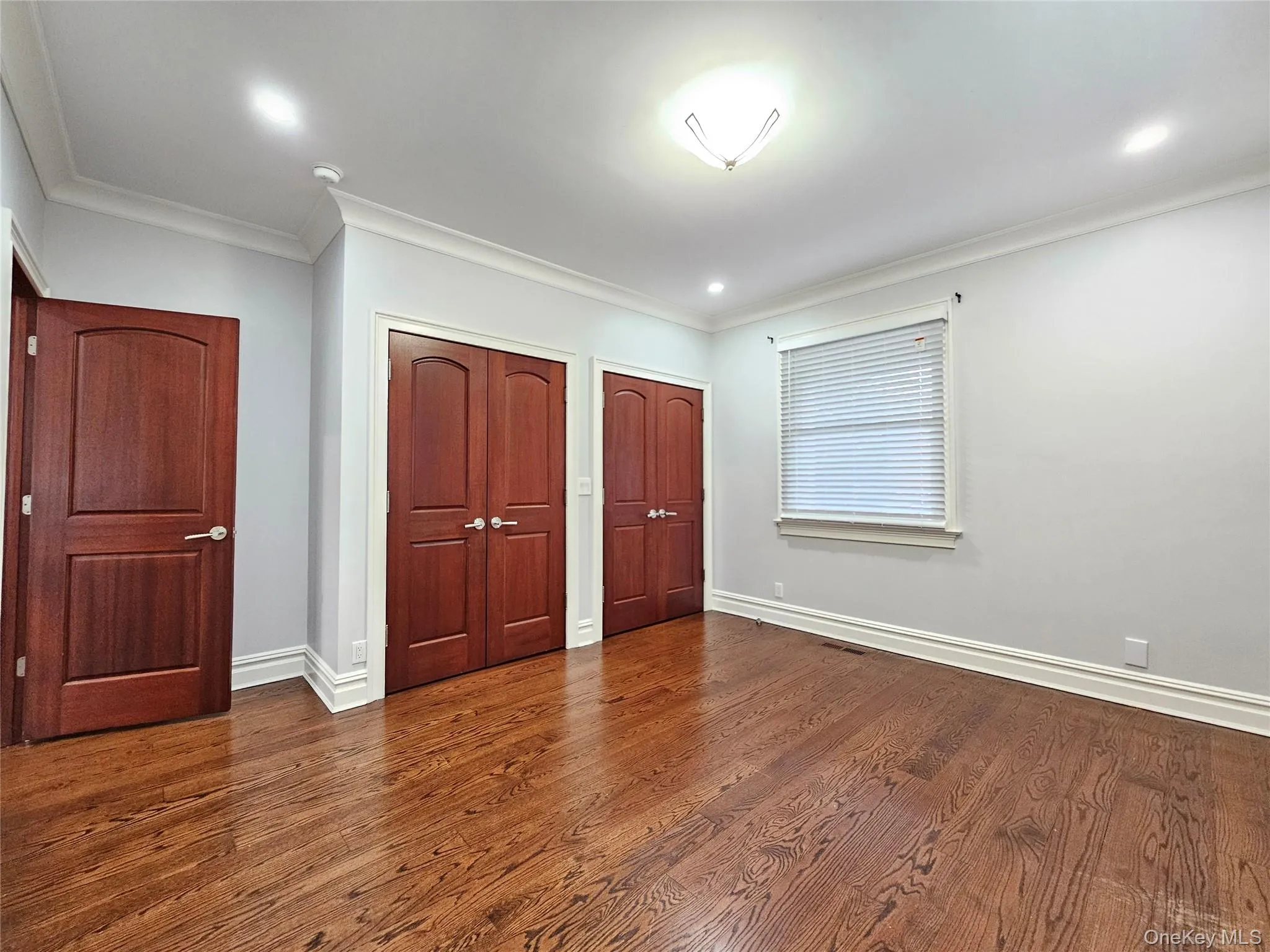 Unfurnished bedroom featuring two closets, crown molding, dark wood-style flooring, and recessed lighting Unfurnished bedroom featuring two closets, crown molding, dark wood-style flooring, and recessed lighting