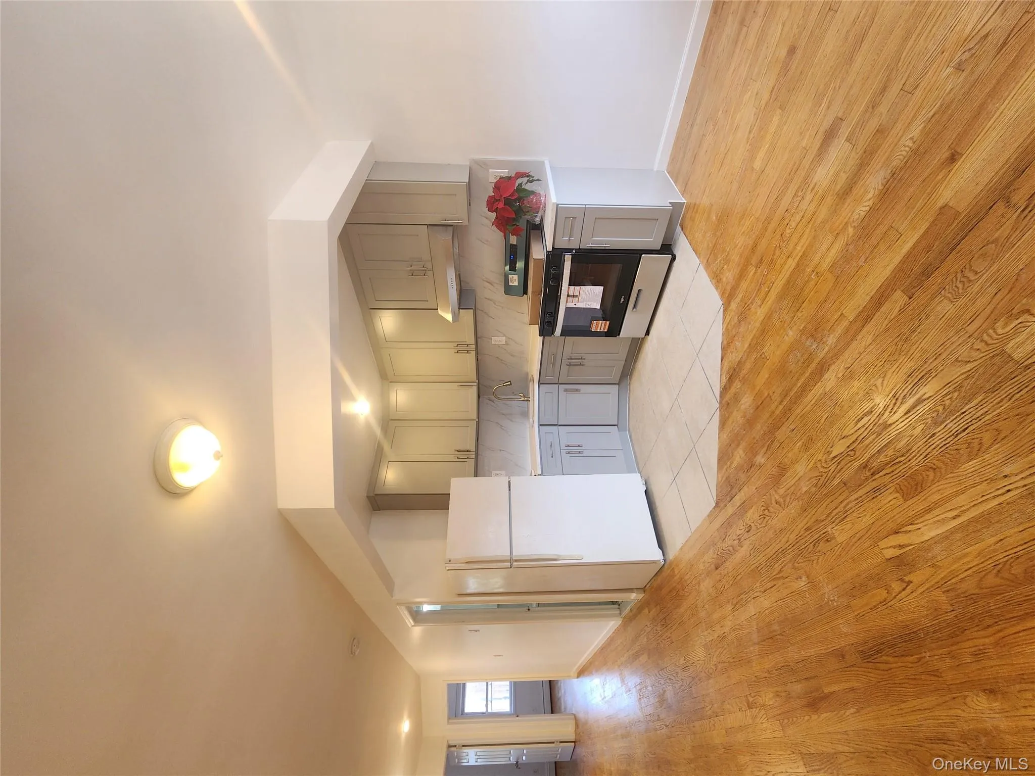 Kitchen featuring fridge, range, light countertops, light wood finished floors, and backsplash Kitchen featuring fridge, range, light countertops, light wood finished floors, and backsplash
