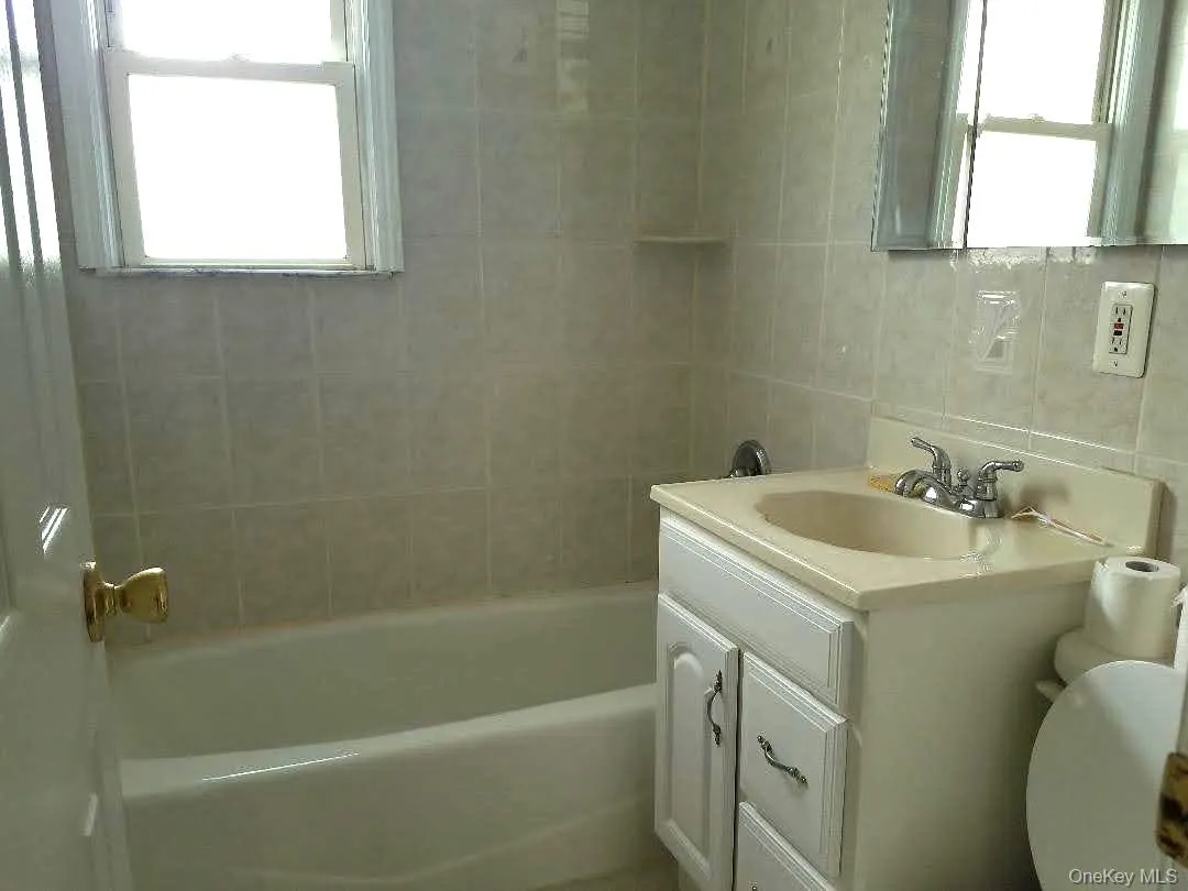 Bathroom featuring vanity, healthy amount of natural light, and tile walls Bathroom featuring vanity, healthy amount of natural light, and tile walls