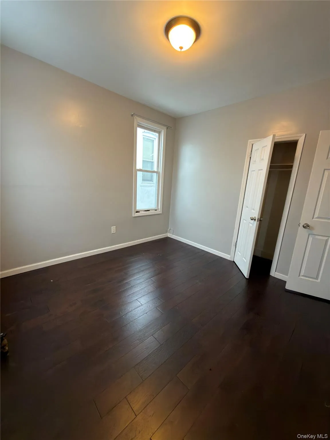 Unfurnished bedroom featuring dark wood-style floors and a closet Unfurnished bedroom featuring dark wood-style floors and a closet