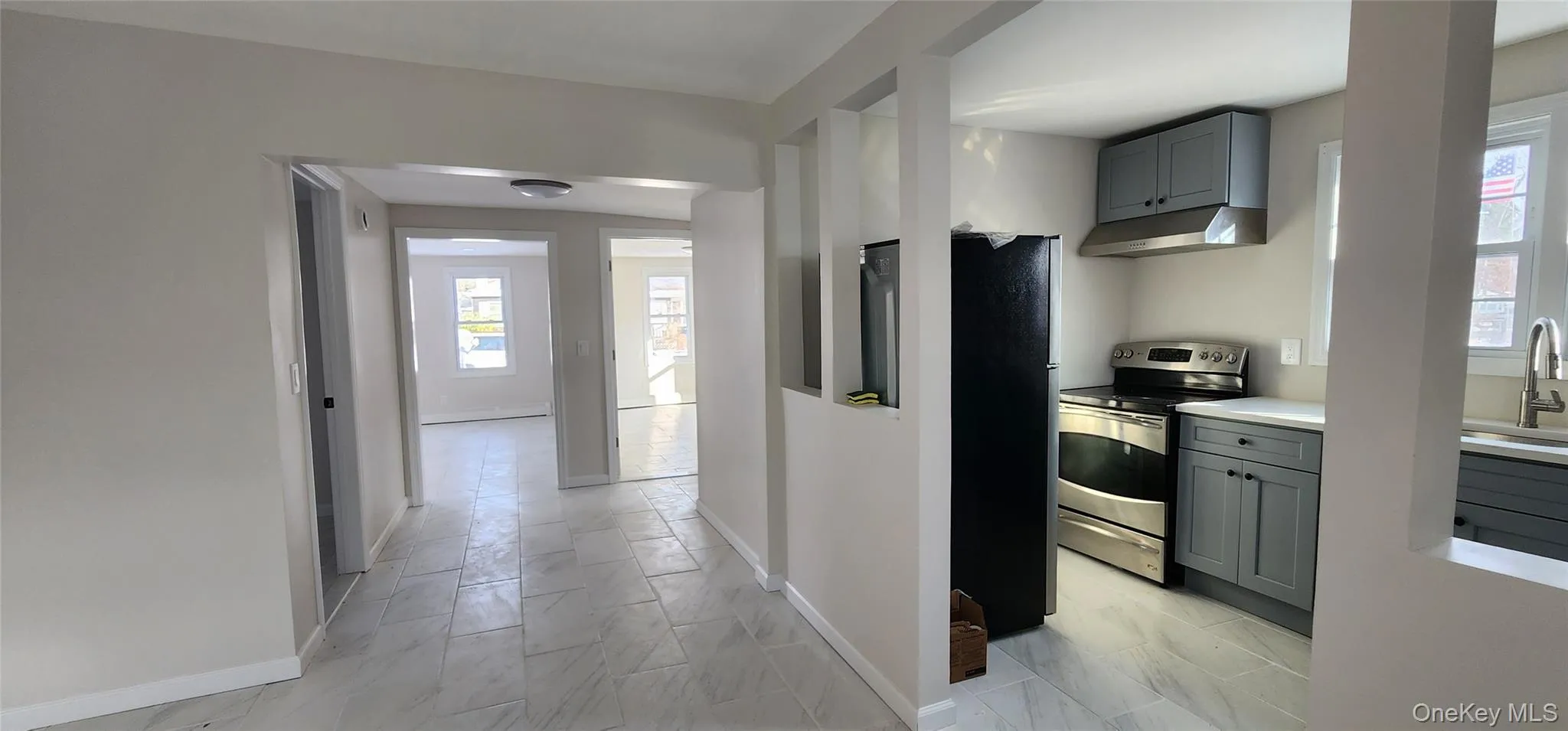 Kitchen featuring gray cabinetry, appliances with stainless steel finishes, under cabinet range hood, and healthy amount of natural light Kitchen featuring gray cabinetry, appliances with stainless steel finishes, under cabinet range hood, and healthy amount of natural light