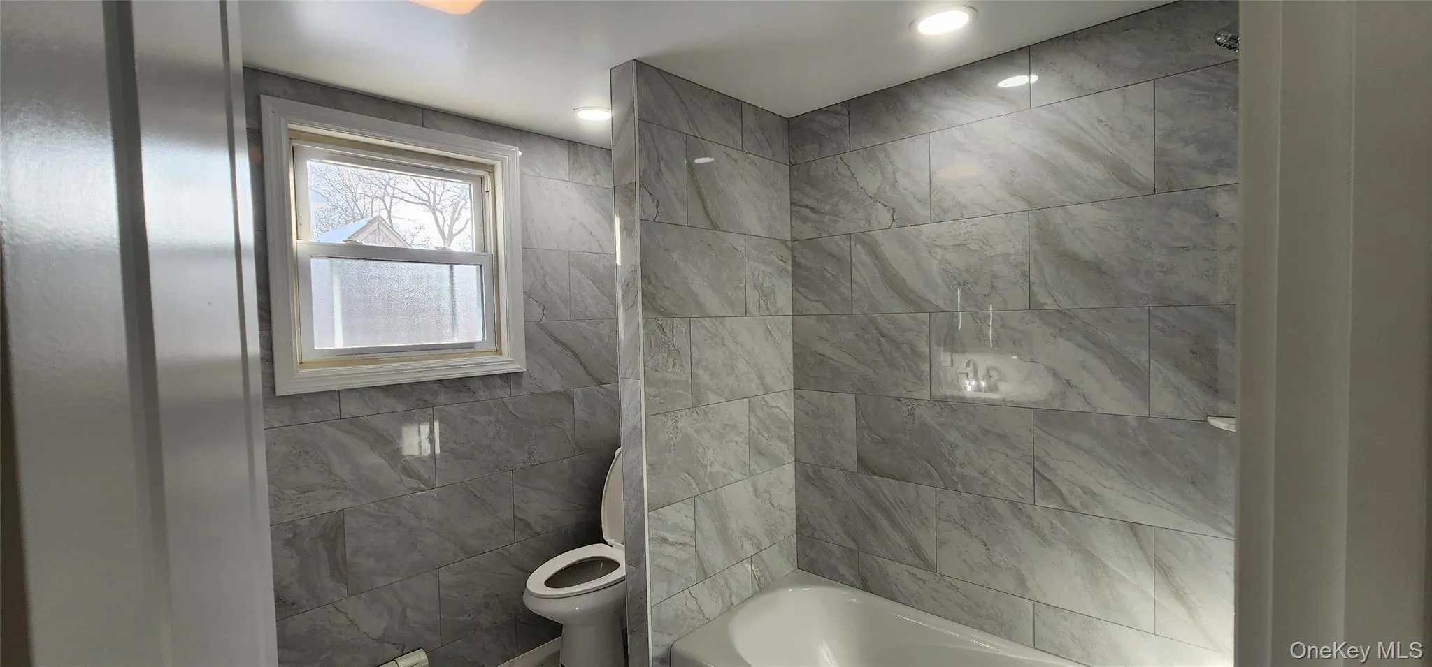 Full bathroom with shower / bathtub combination and tile walls Full bathroom with shower / bathtub combination and tile walls