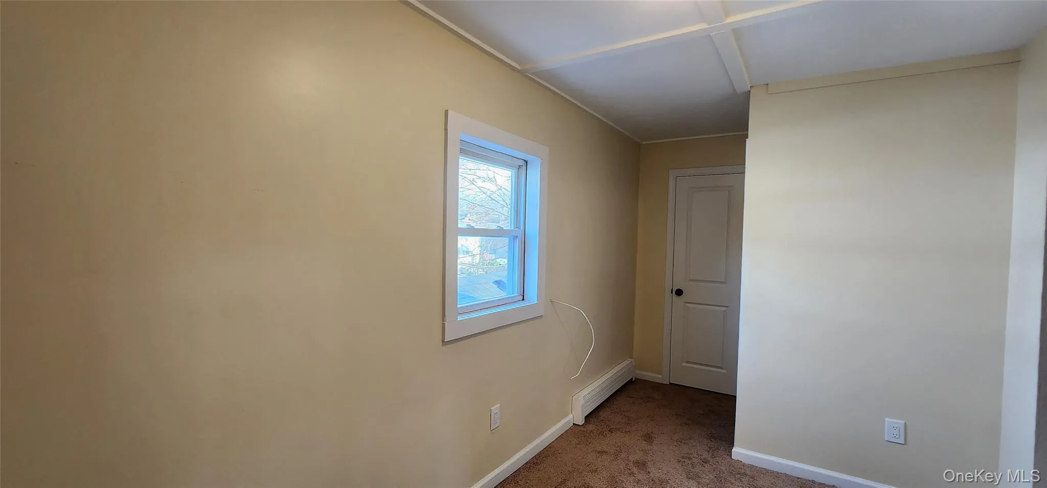 Carpeted spare room with baseboards and a baseboard heating unit Carpeted spare room with baseboards and a baseboard heating unit