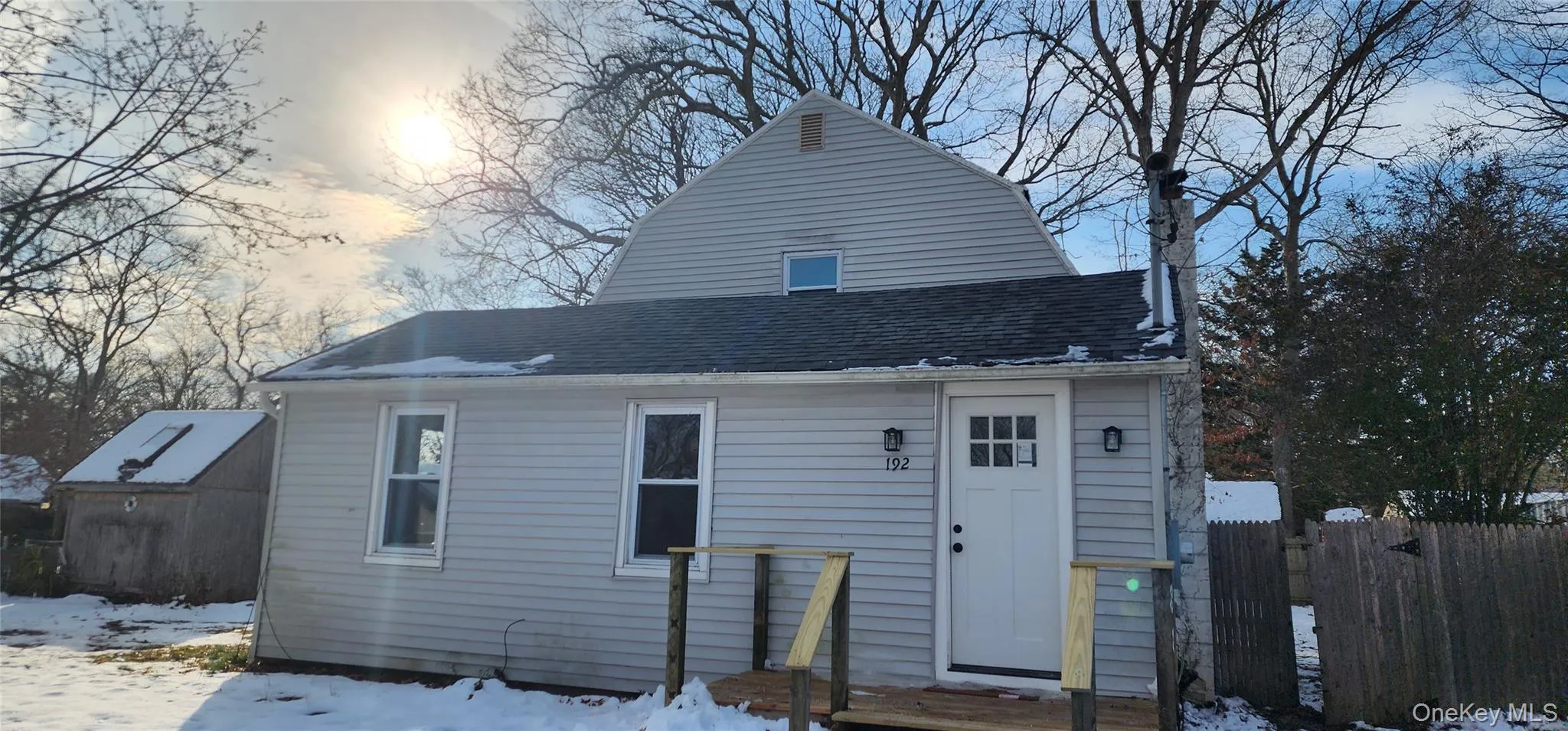Snow covered back of property featuring a shingled roof Snow covered back of property featuring a shingled roof