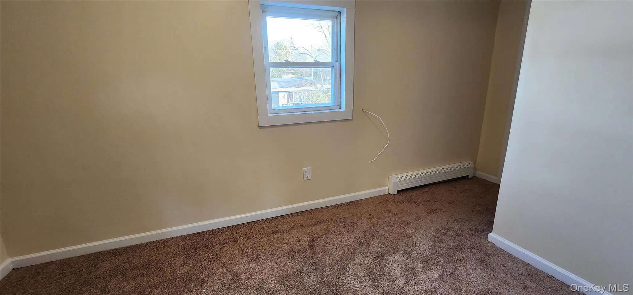 Carpeted empty room with a baseboard heating unit and baseboards Carpeted empty room with a baseboard heating unit and baseboards