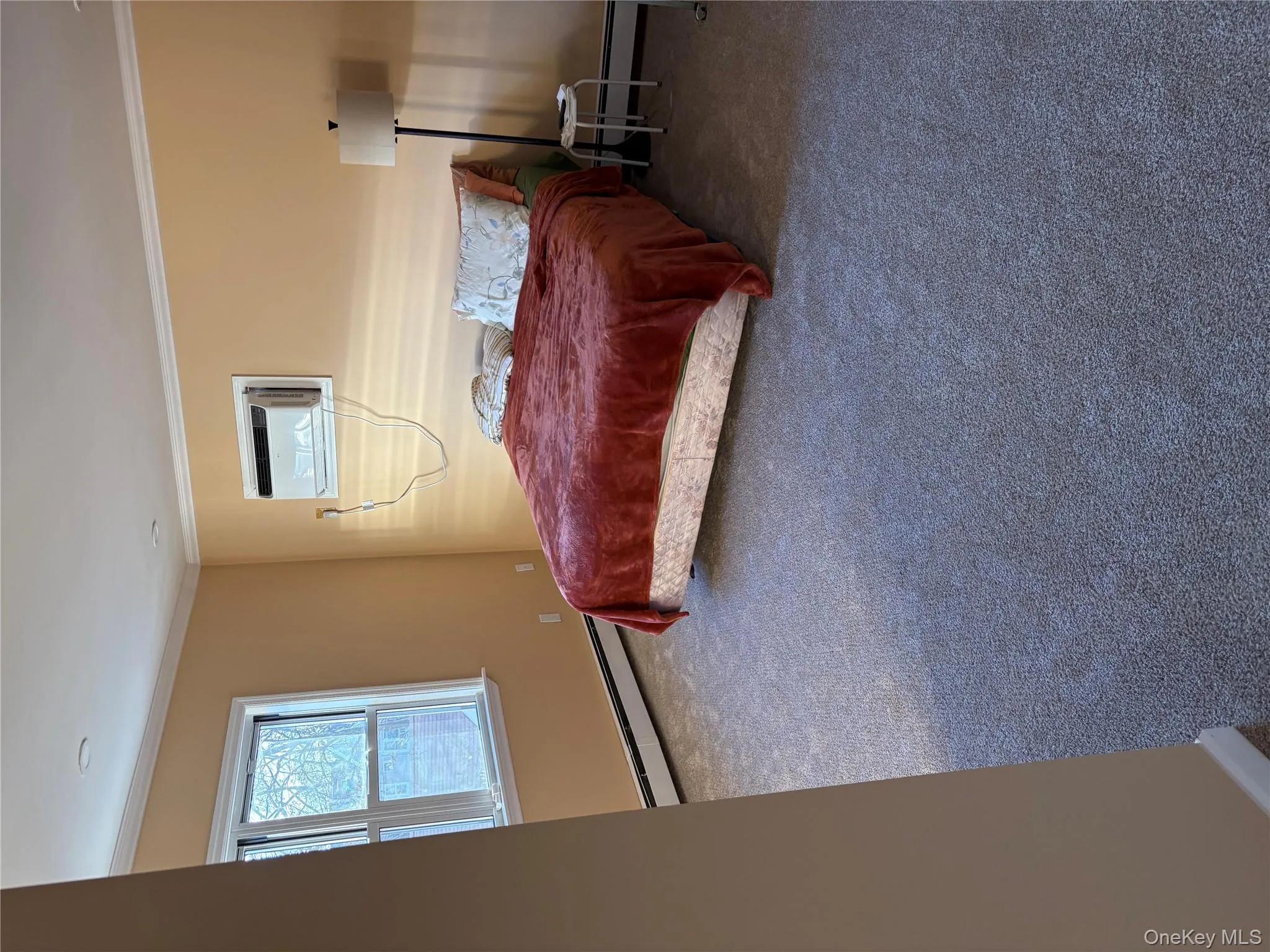 Bedroom featuring crown molding, baseboard heating, carpet flooring, and a wall mounted air conditioner Bedroom featuring crown molding, baseboard heating, carpet flooring, and a wall mounted air conditioner