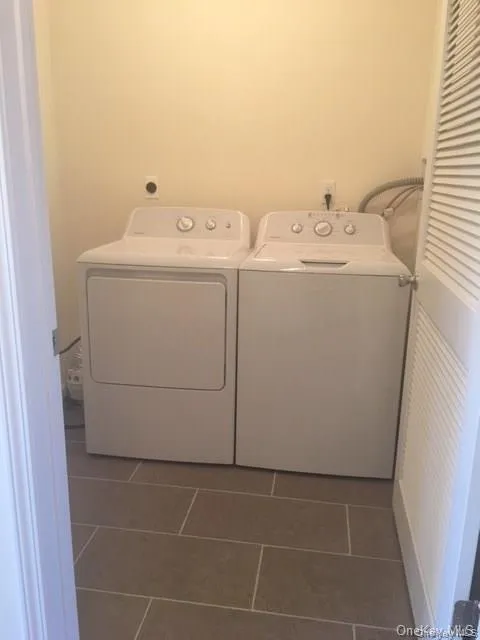 Washroom featuring dark tile patterned floors and separate washer and dryer Washroom featuring dark tile patterned floors and separate washer and dryer