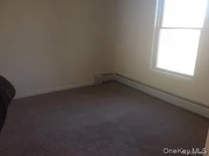 Unfurnished room featuring a baseboard heating unit and dark carpet Unfurnished room featuring a baseboard heating unit and dark carpet