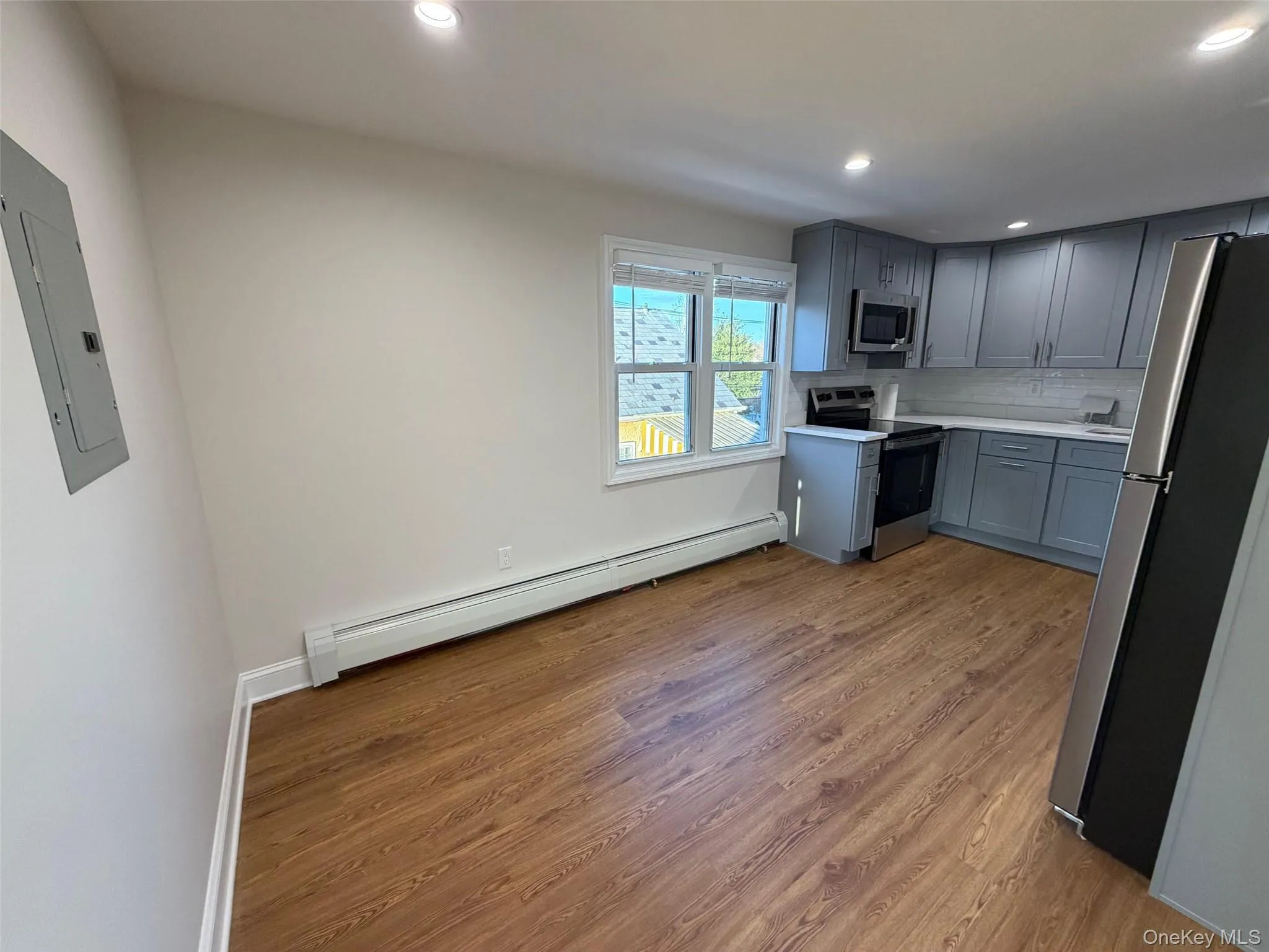 Kitchen featuring gray cabinets, appliances with stainless steel finishes, light countertops, baseboard heating, and recessed lighting Kitchen featuring gray cabinets, appliances with stainless steel finishes, light countertops, baseboard heating, and recessed lighting