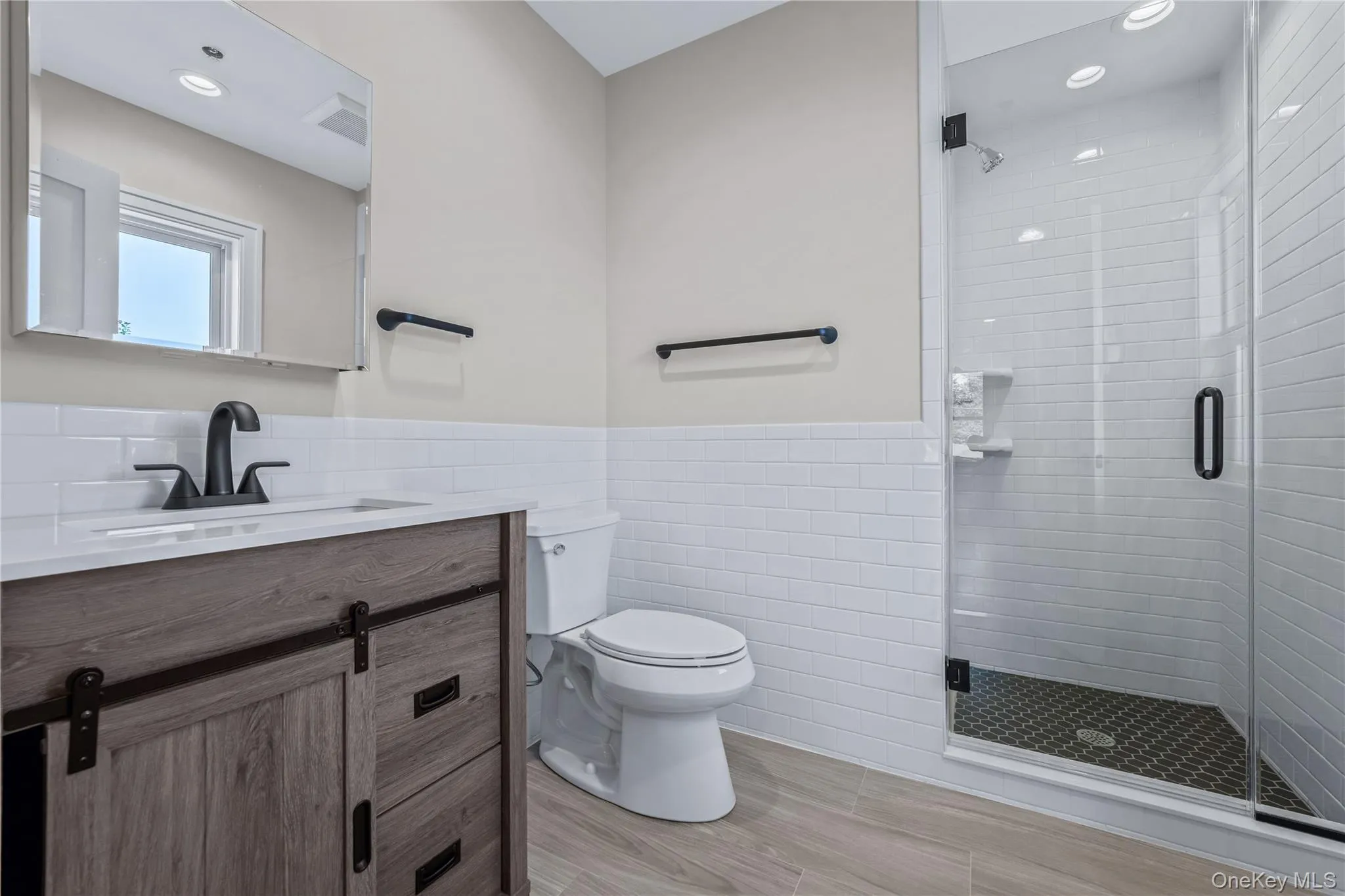 Full bath with vanity, a stall shower, a wainscoted wall, tile walls, and recessed lighting Full bath with vanity, a stall shower, a wainscoted wall, tile walls, and recessed lighting