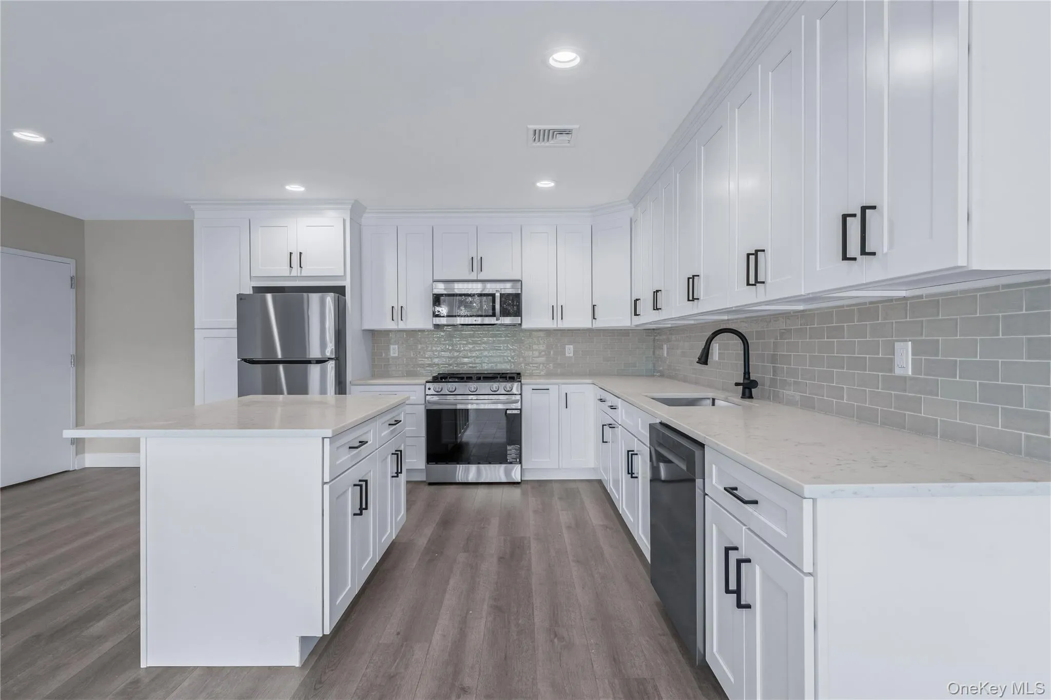 Kitchen featuring stainless steel appliances, white cabinetry, a kitchen island, light stone countertops, and light wood-type flooring Kitchen featuring stainless steel appliances, white cabinetry, a kitchen island, light stone countertops, and light wood-type flooring