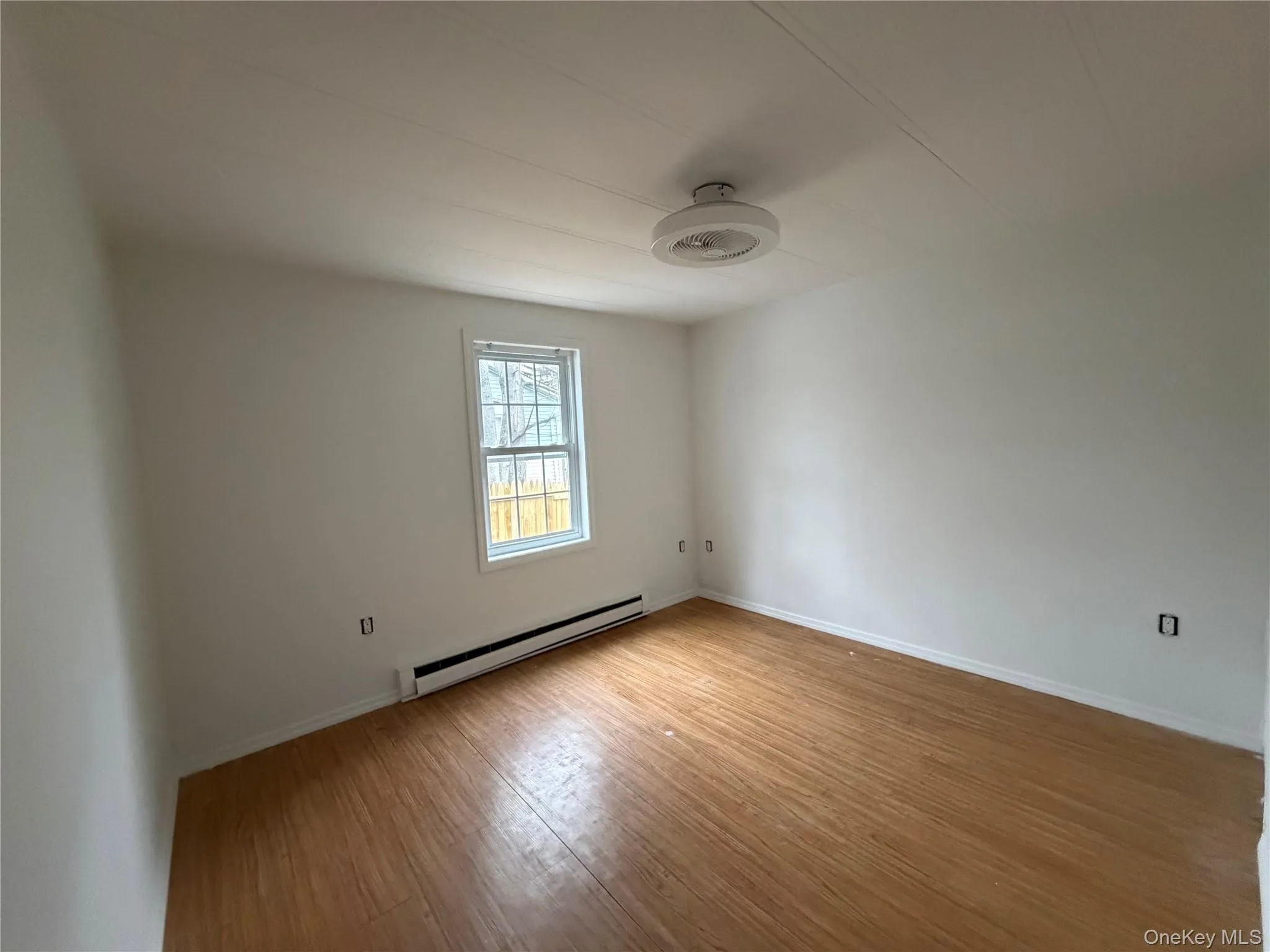 Unfurnished room featuring baseboard heating and light wood-style flooring Unfurnished room featuring baseboard heating and light wood-style flooring