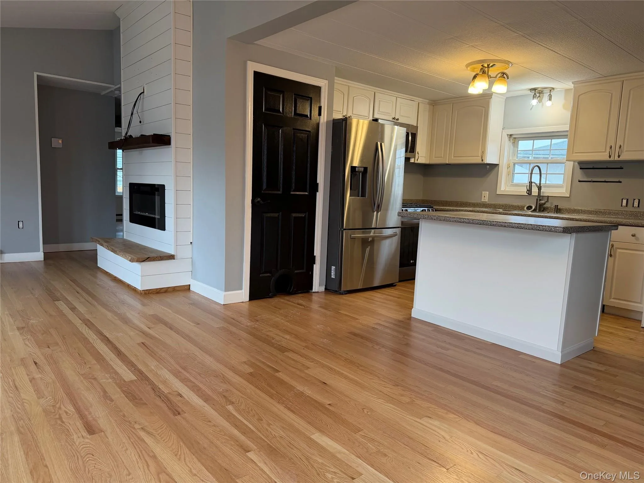 Kitchen featuring stainless steel appliances, a center island, light wood finished floors, and a fireplace Kitchen featuring stainless steel appliances, a center island, light wood finished floors, and a fireplace
