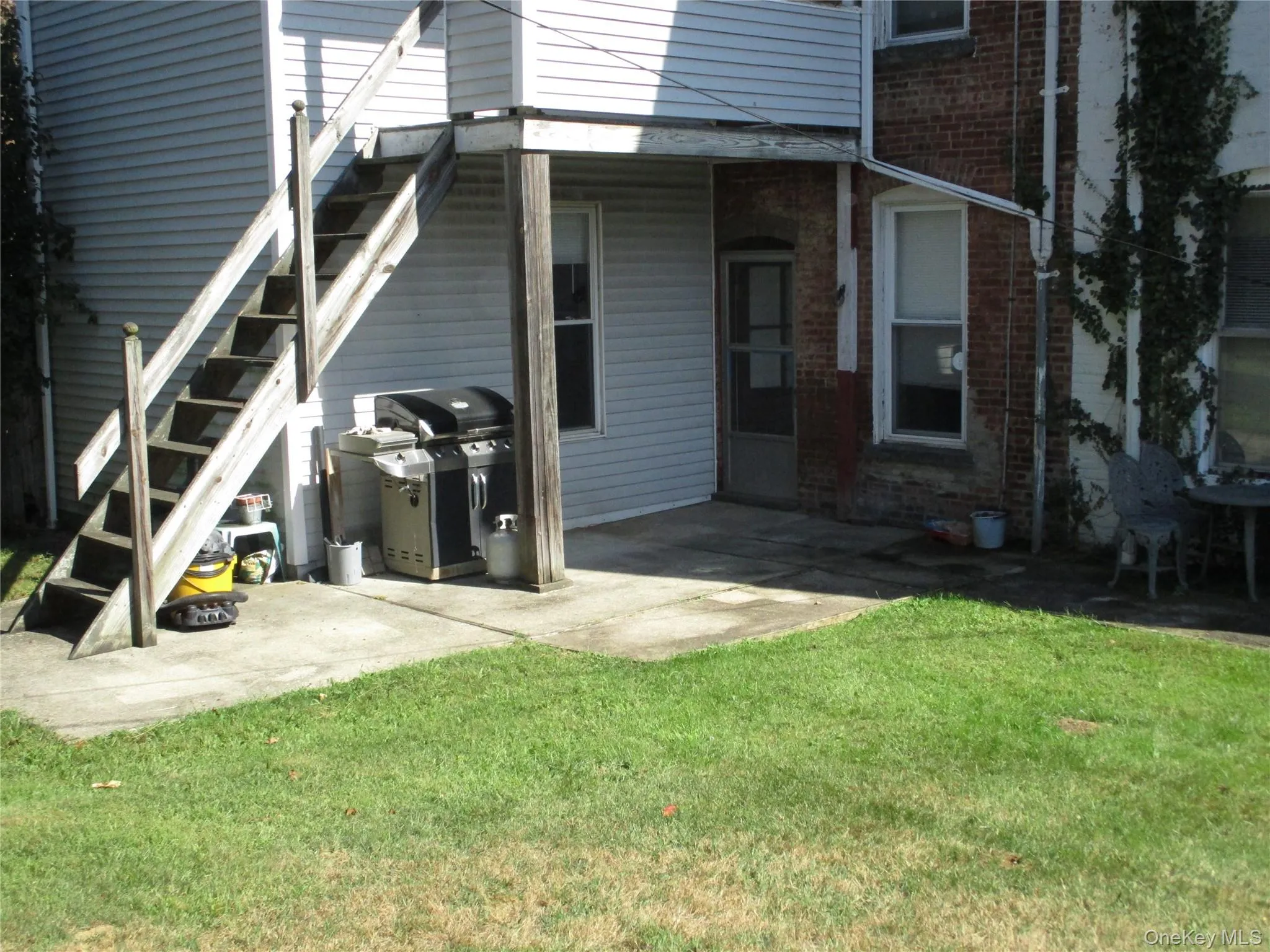 Rear view of property with a patio area, stairs, brick siding, and a yard Rear view of property with a patio area, stairs, brick siding, and a yard