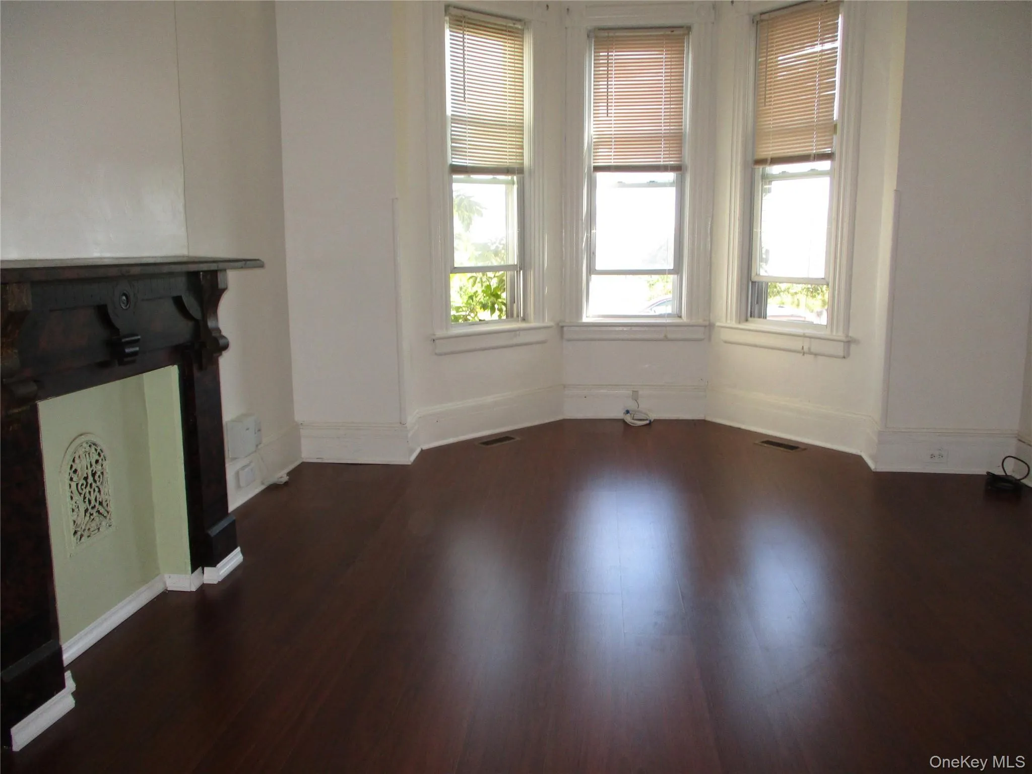 Unfurnished living room with healthy amount of natural light and dark wood-type flooring Unfurnished living room with healthy amount of natural light and dark wood-type flooring