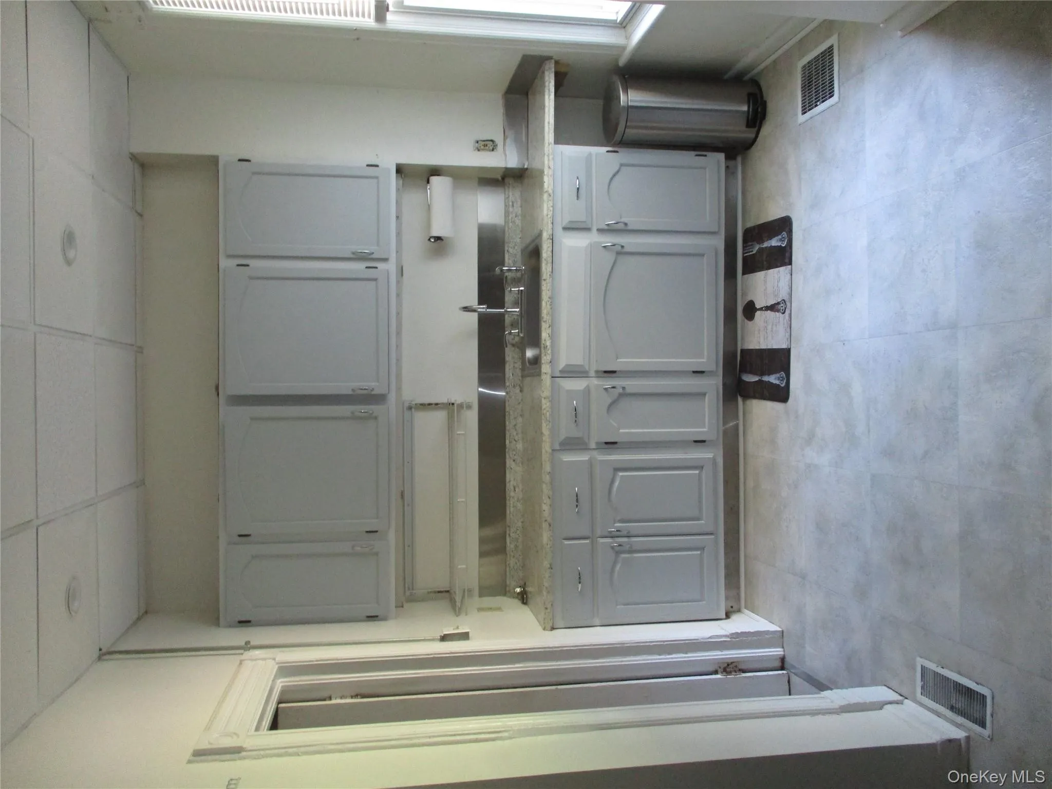 Kitchen with gray cabinetry, healthy amount of natural light, a paneled ceiling, and light flooring Kitchen with gray cabinetry, healthy amount of natural light, a paneled ceiling, and light flooring