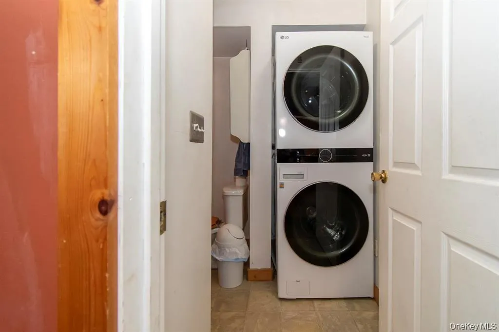 Washroom with estacked washer and dryer and tile patterned floors Washroom with estacked washer and dryer and tile patterned floors