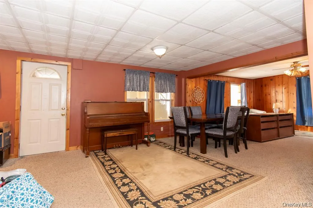 Dining space featuring wooden walls and light colored carpet Dining space featuring wooden walls and light colored carpet
