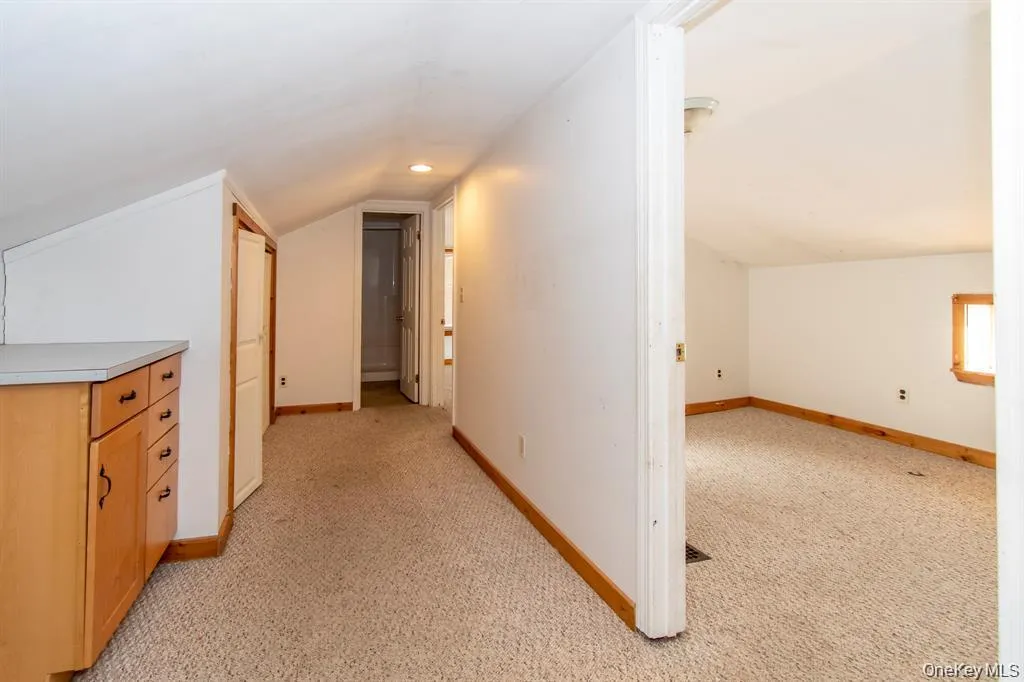 Corridor featuring light carpet and lofted ceiling Corridor featuring light carpet and lofted ceiling