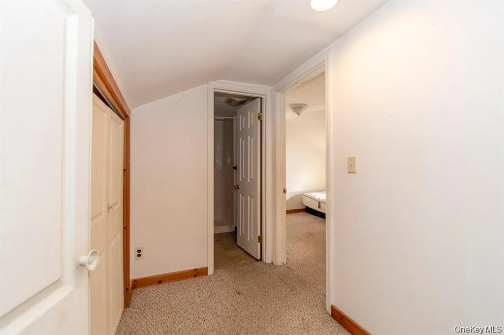 Corridor featuring light carpet and lofted ceiling Corridor featuring light carpet and lofted ceiling