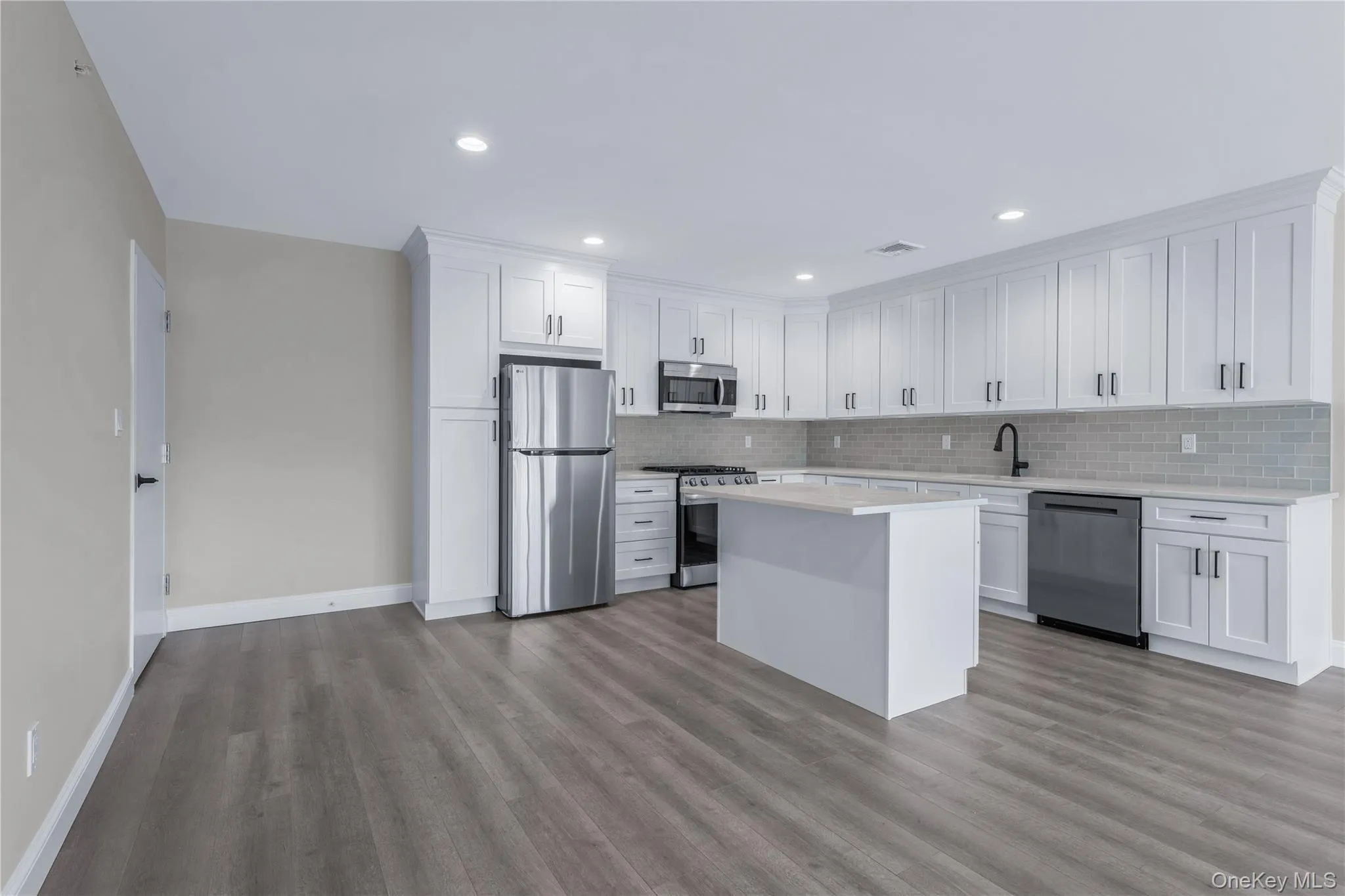 Kitchen featuring appliances with stainless steel finishes, white cabinetry, a kitchen island, light wood-type flooring, and recessed lighting Kitchen featuring appliances with stainless steel finishes, white cabinetry, a kitchen island, light wood-type flooring, and recessed lighting