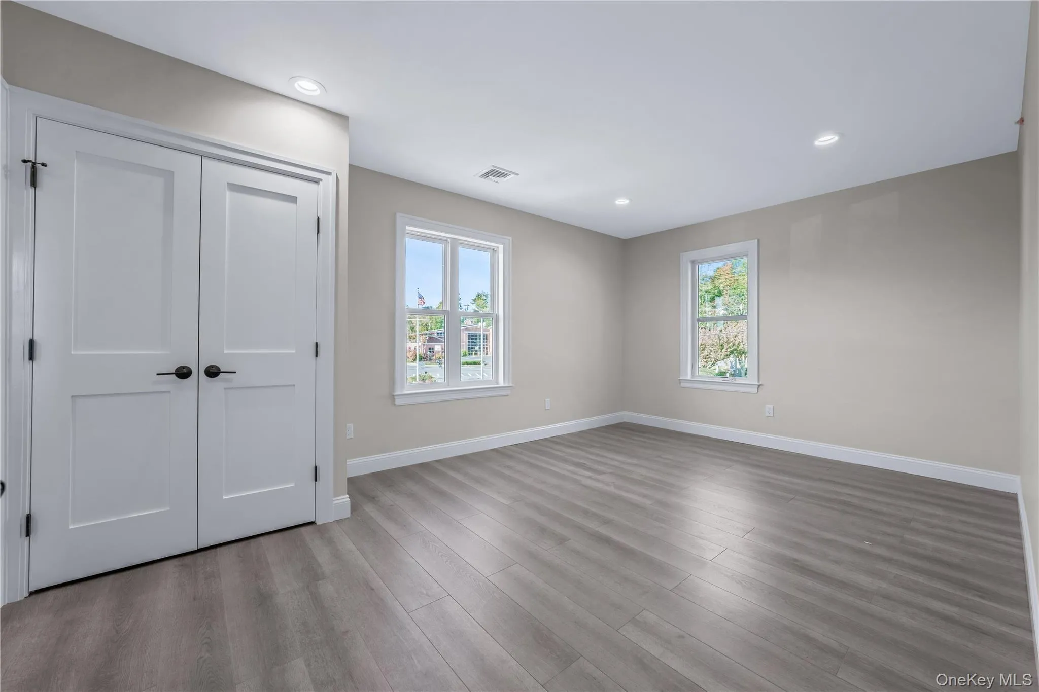 Unfurnished bedroom featuring multiple windows, wood finished floors, a closet, and recessed lighting Unfurnished bedroom featuring multiple windows, wood finished floors, a closet, and recessed lighting