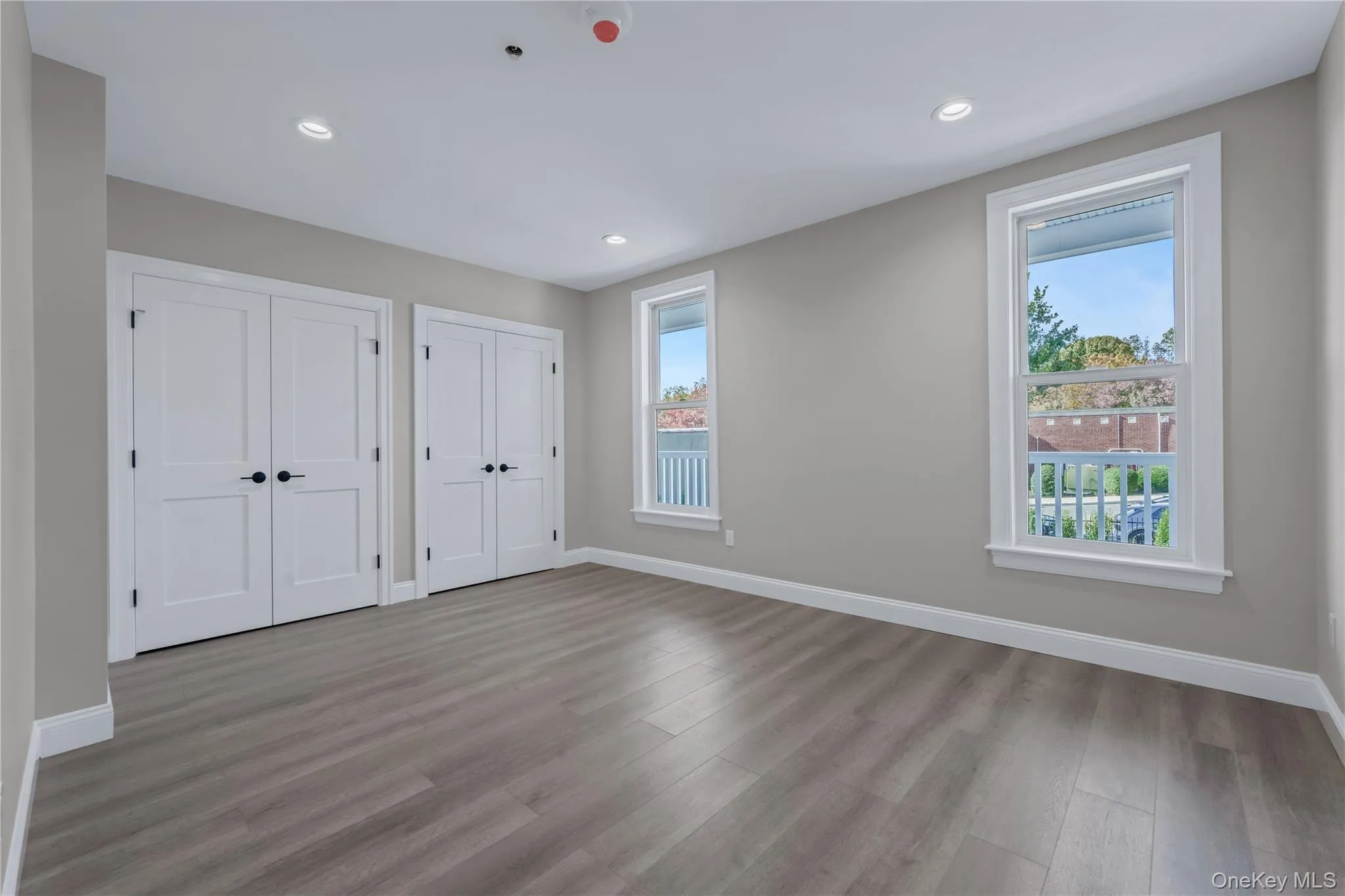 Unfurnished bedroom with multiple closets, wood finished floors, and recessed lighting Unfurnished bedroom with multiple closets, wood finished floors, and recessed lighting