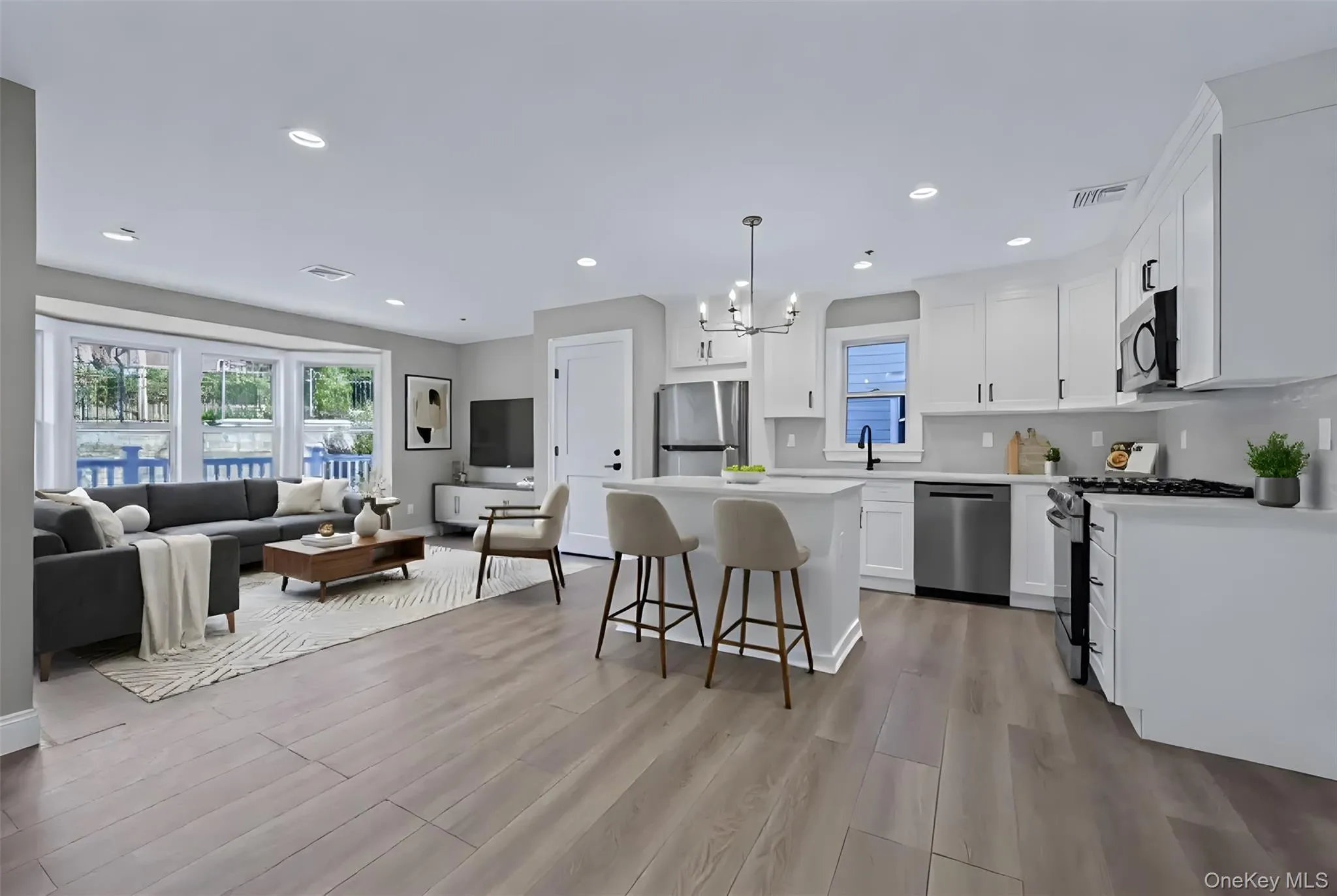 Kitchen featuring open floor plan, a chandelier, pendant lighting, appliances with stainless steel finishes, and a kitchen breakfast bar Kitchen featuring open floor plan, a chandelier, pendant lighting, appliances with stainless steel finishes, and a kitchen breakfast bar