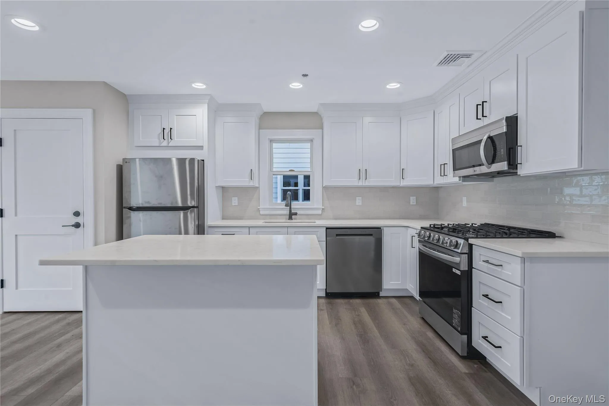 Kitchen featuring appliances with stainless steel finishes, white cabinetry, light stone counters, a kitchen island, and recessed lighting Kitchen featuring appliances with stainless steel finishes, white cabinetry, light stone counters, a kitchen island, and recessed lighting