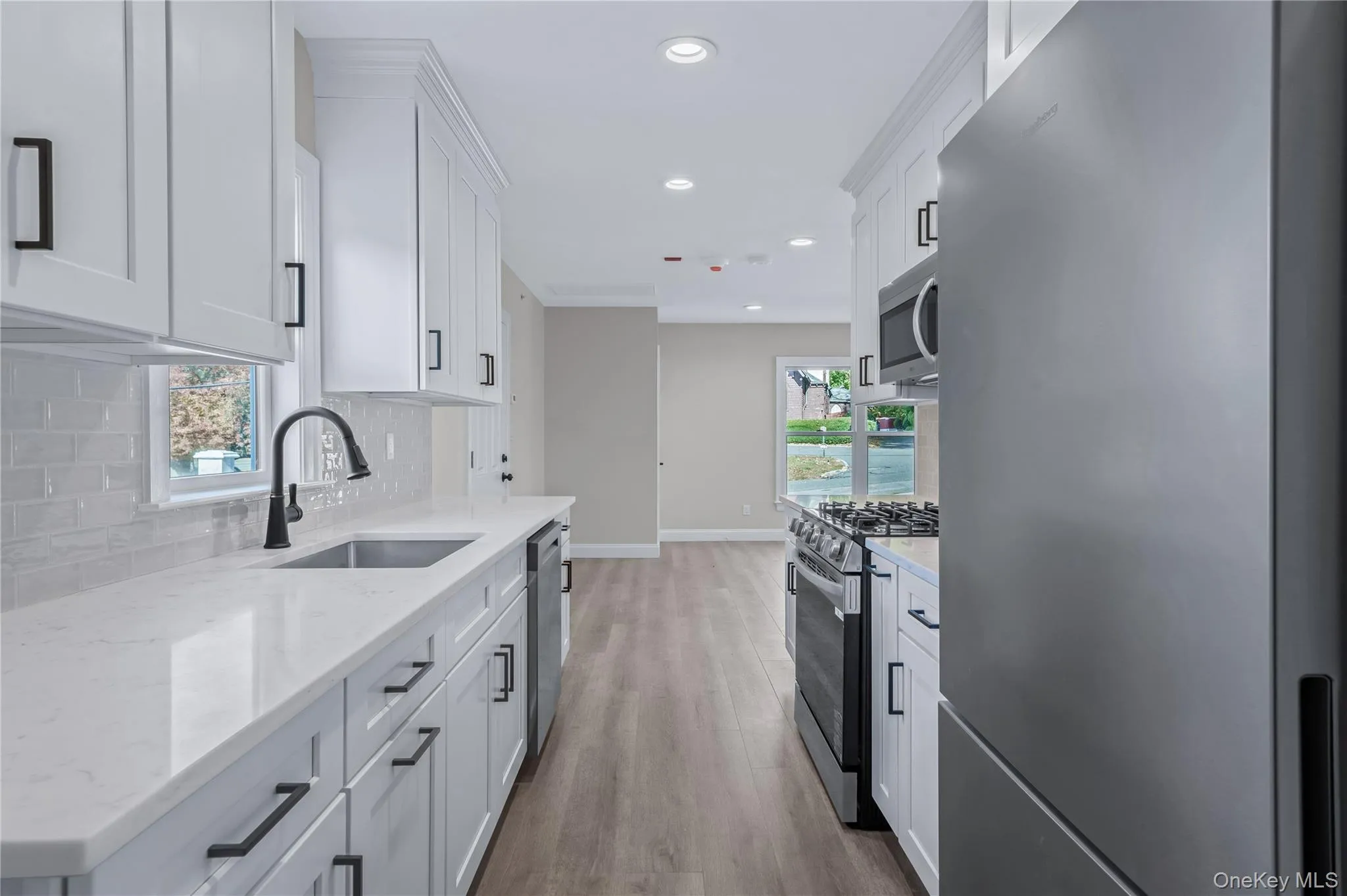 Kitchen featuring appliances with stainless steel finishes, recessed lighting, light stone counters, white cabinetry, and light wood-style floors Kitchen featuring appliances with stainless steel finishes, recessed lighting, light stone counters, white cabinetry, and light wood-style floors