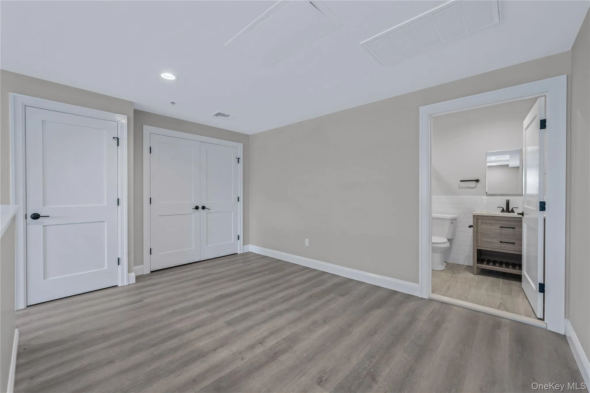 Unfurnished bedroom with light wood-style flooring, a closet, connected bathroom, and recessed lighting Unfurnished bedroom with light wood-style flooring, a closet, connected bathroom, and recessed lighting