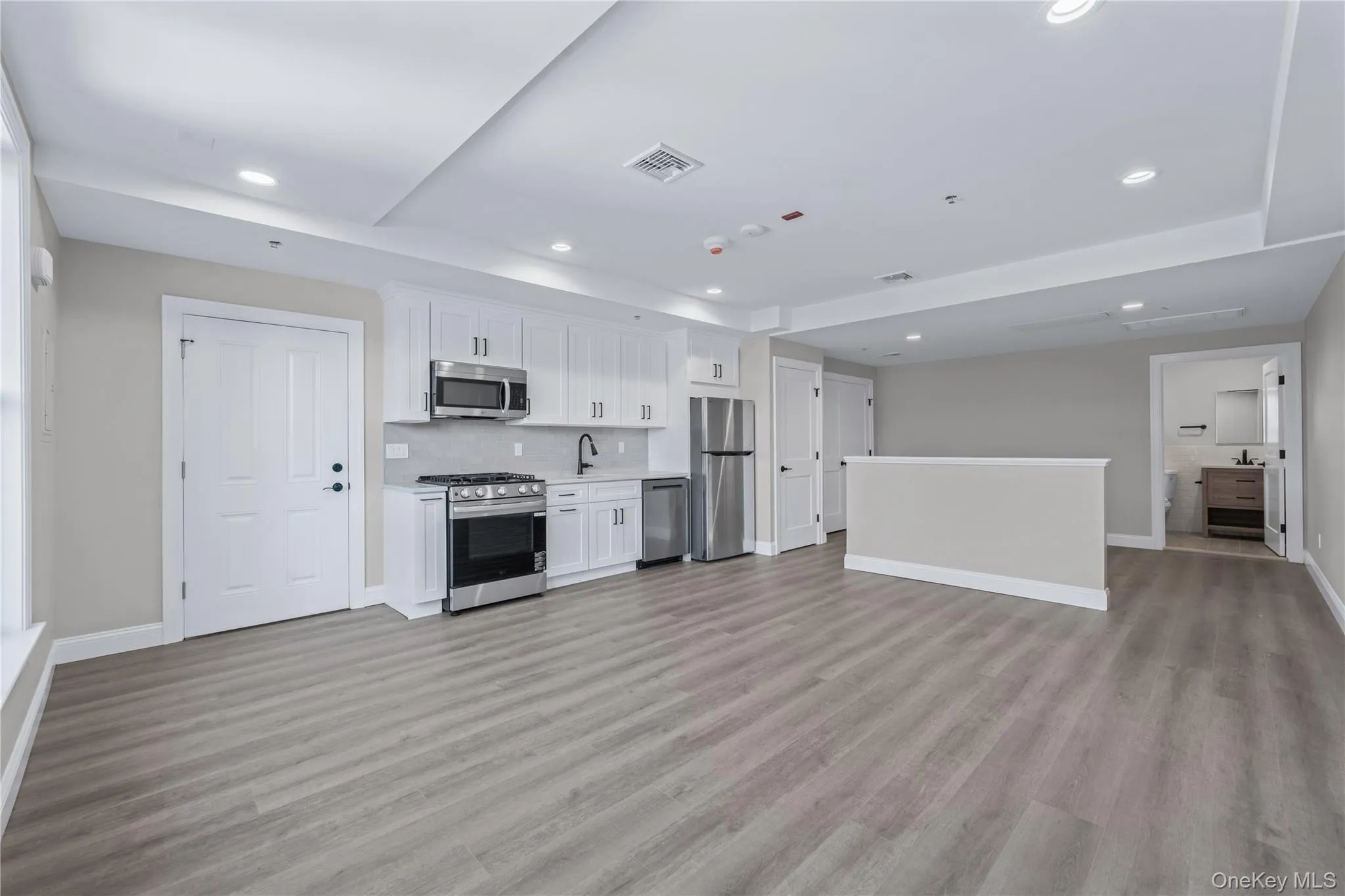 Kitchen with white cabinets, appliances with stainless steel finishes, open floor plan, light countertops, and recessed lighting Kitchen with white cabinets, appliances with stainless steel finishes, open floor plan, light countertops, and recessed lighting
