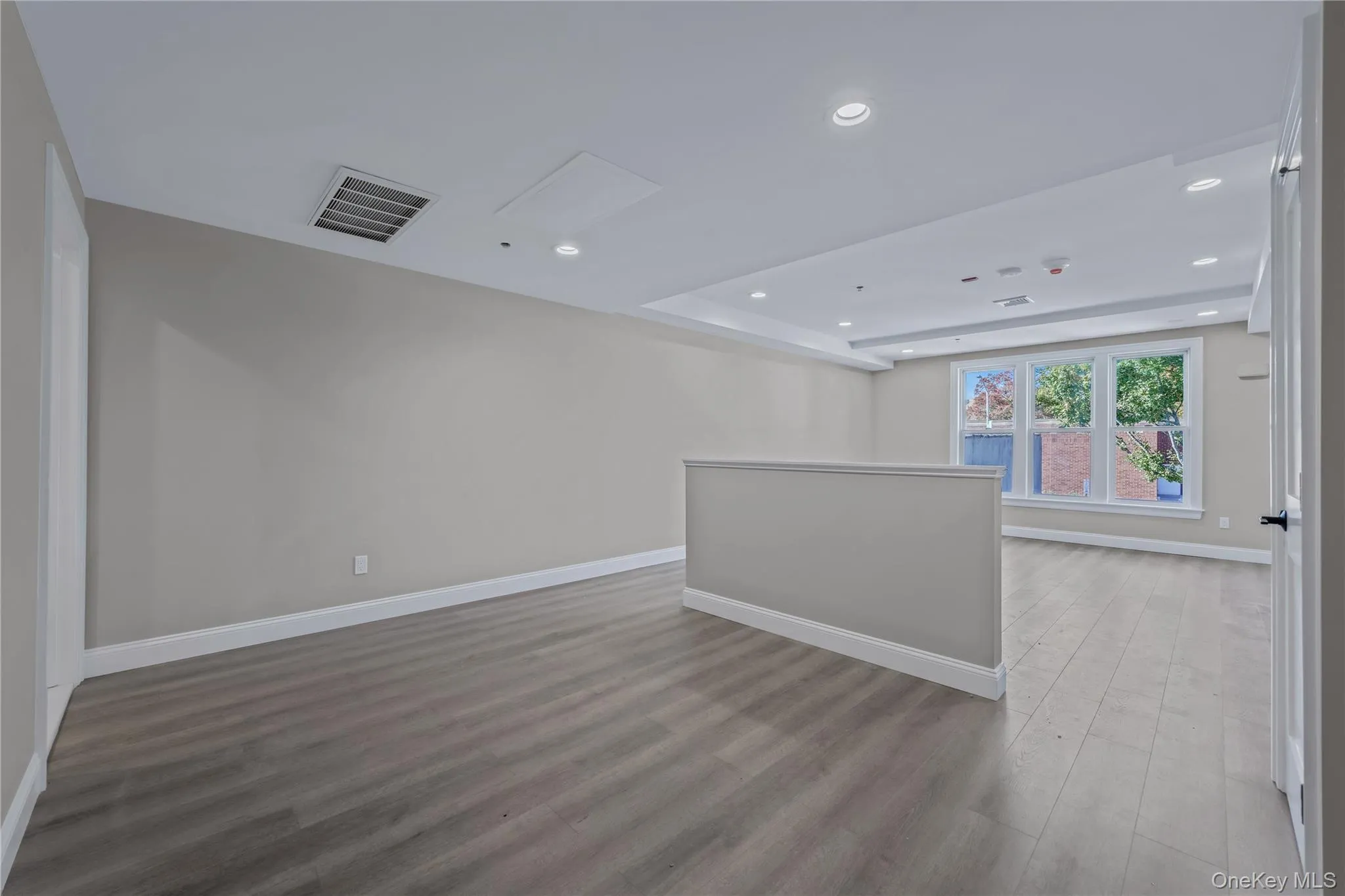 Unfurnished room with recessed lighting, wood finished floors, and a tray ceiling Unfurnished room with recessed lighting, wood finished floors, and a tray ceiling