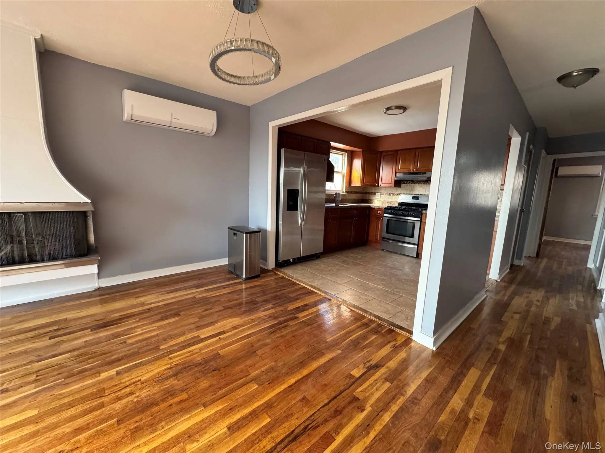 Kitchen with stainless steel appliances, light wood-style floors, a wall mounted air conditioner, decorative light fixtures, and open floor plan Kitchen with stainless steel appliances, light wood-style floors, a wall mounted air conditioner, decorative light fixtures, and open floor plan