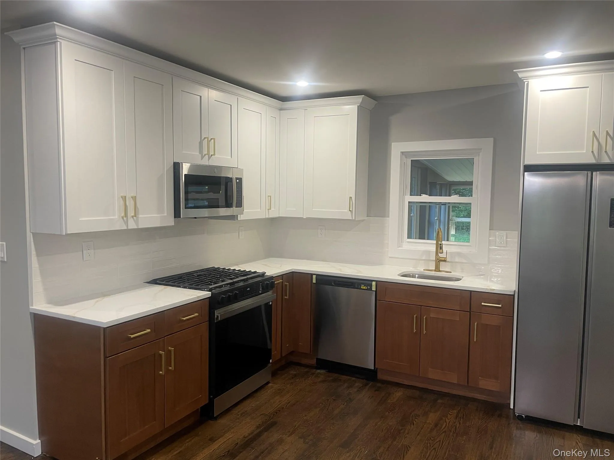 Kitchen featuring appliances with stainless steel finishes, white cabinets, dark wood-style flooring, and tasteful backsplash Kitchen featuring appliances with stainless steel finishes, white cabinets, dark wood-style flooring, and tasteful backsplash