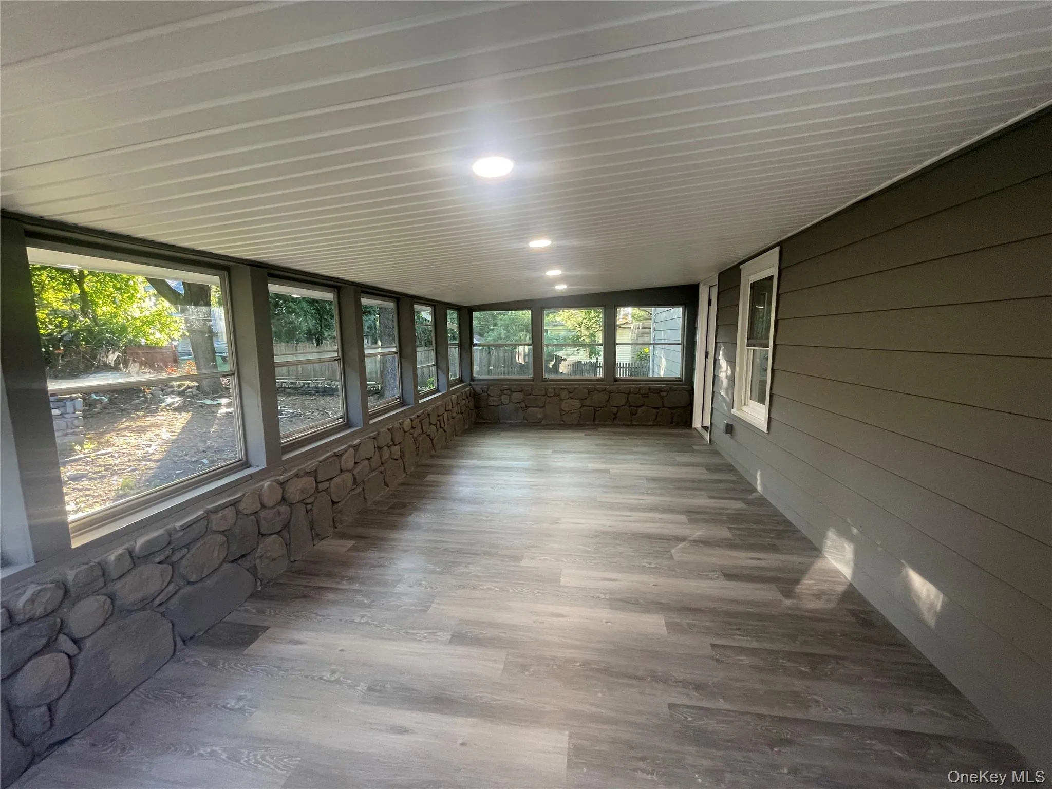 Unfurnished sunroom featuring wood finished floors Unfurnished sunroom featuring wood finished floors